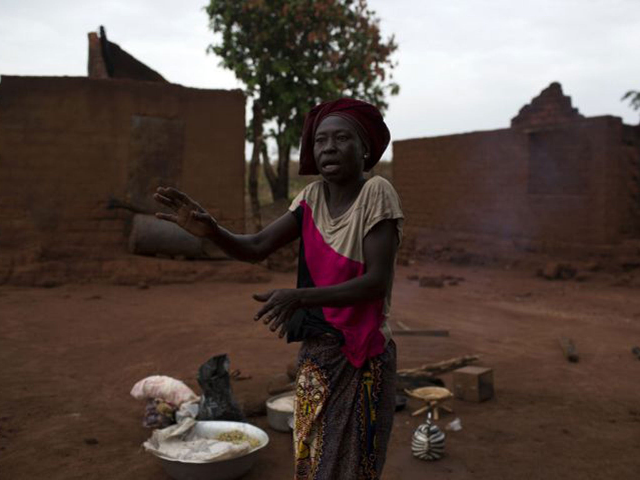 A woman gestures near her destroyed home after her village was almost completely destroyed during a Seleka attack