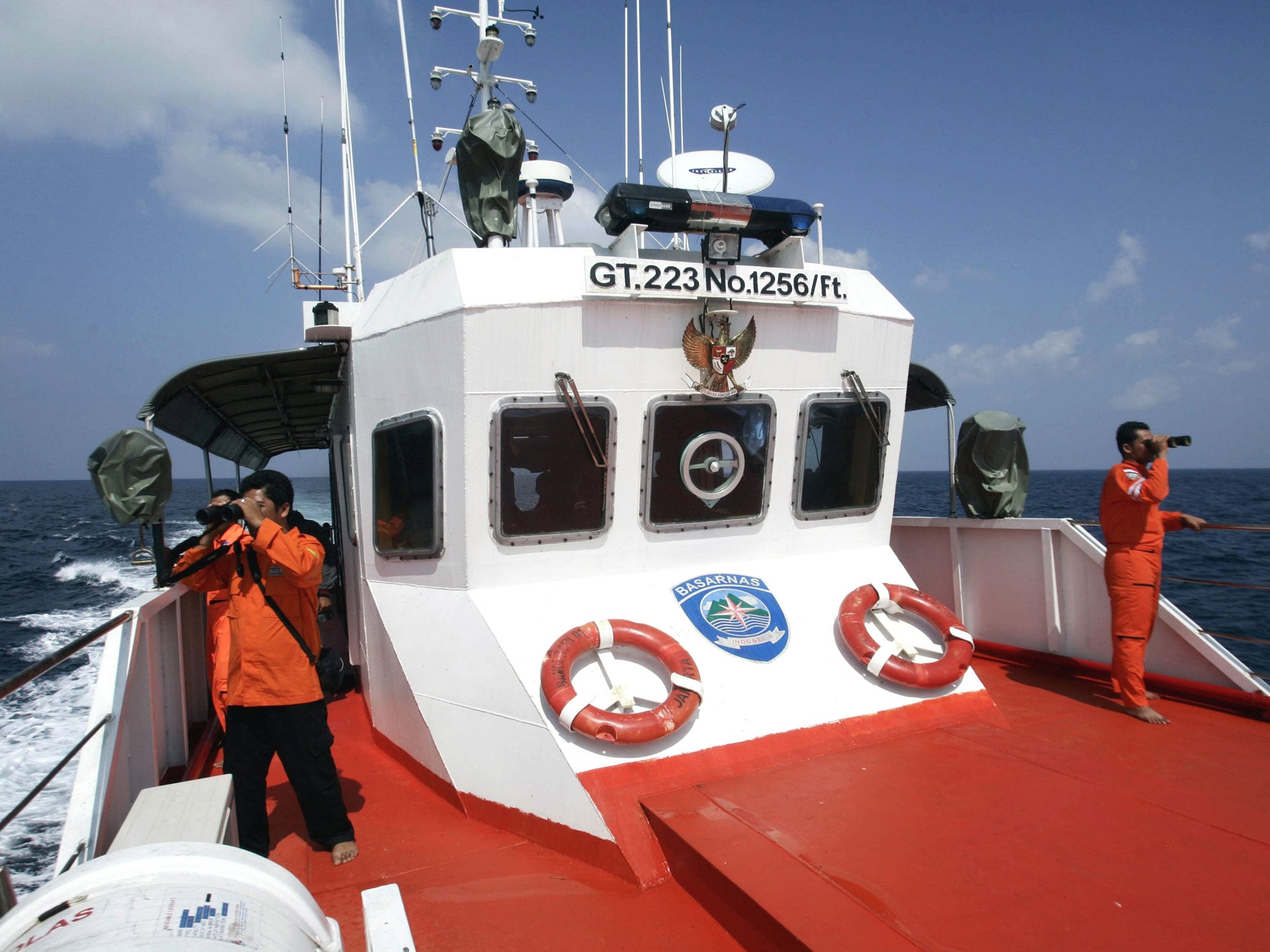 Rescue members use binoculars to look for the missing Malaysia Airlines flight MH370