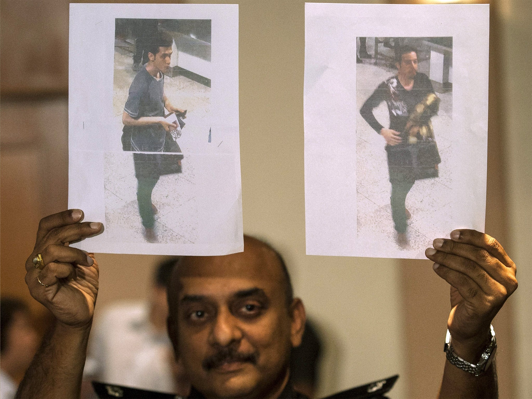 A Malaysian Police officer holds photos of two suspects believed to have travelled with stolen passports on the missing Malaysian Airlines flight