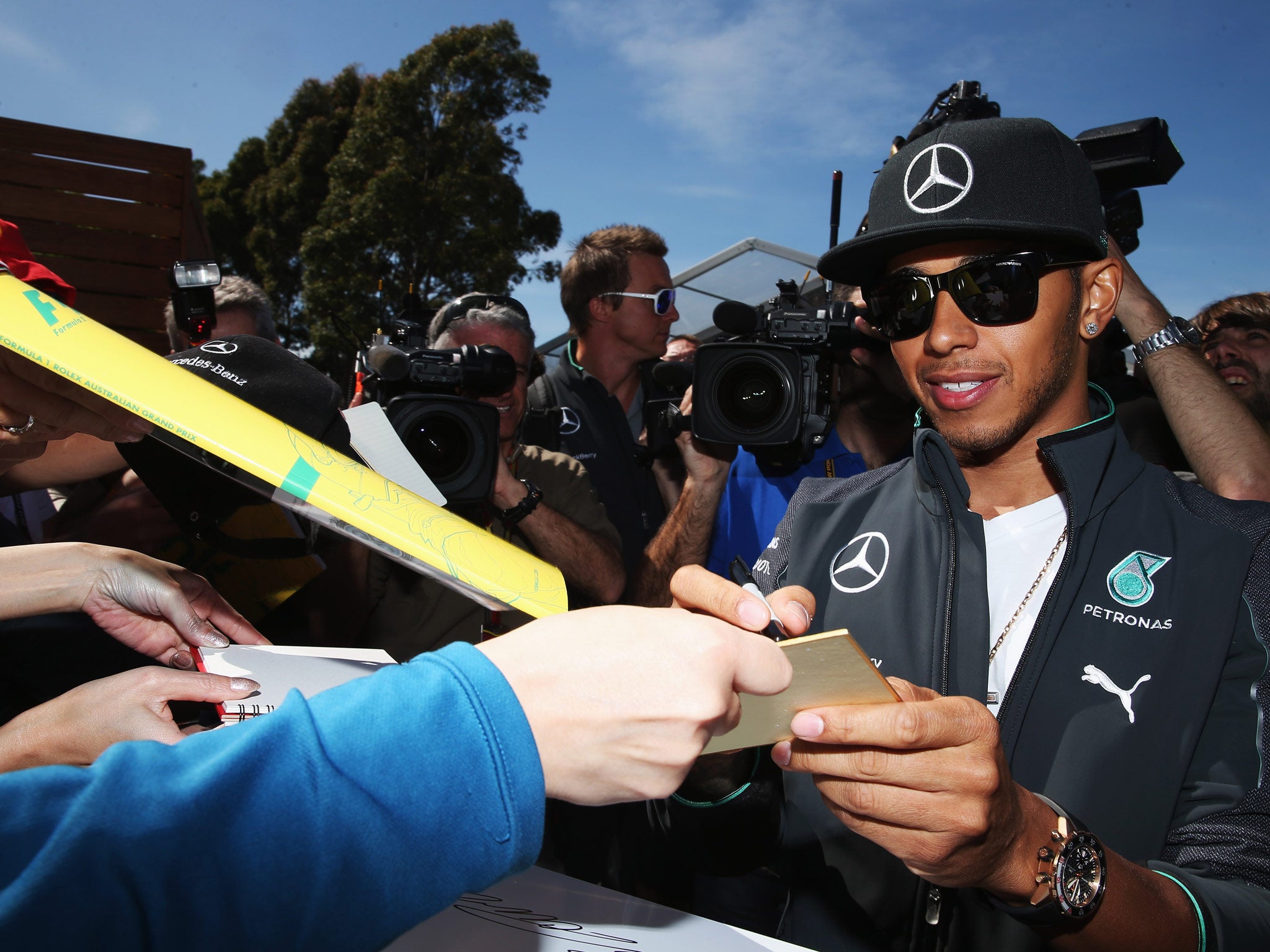 Lewis Hamilton of Great Britain and Mercedes GP signs autographs for fans during previews to the Australian Formula One Grand Prix at Albert Park