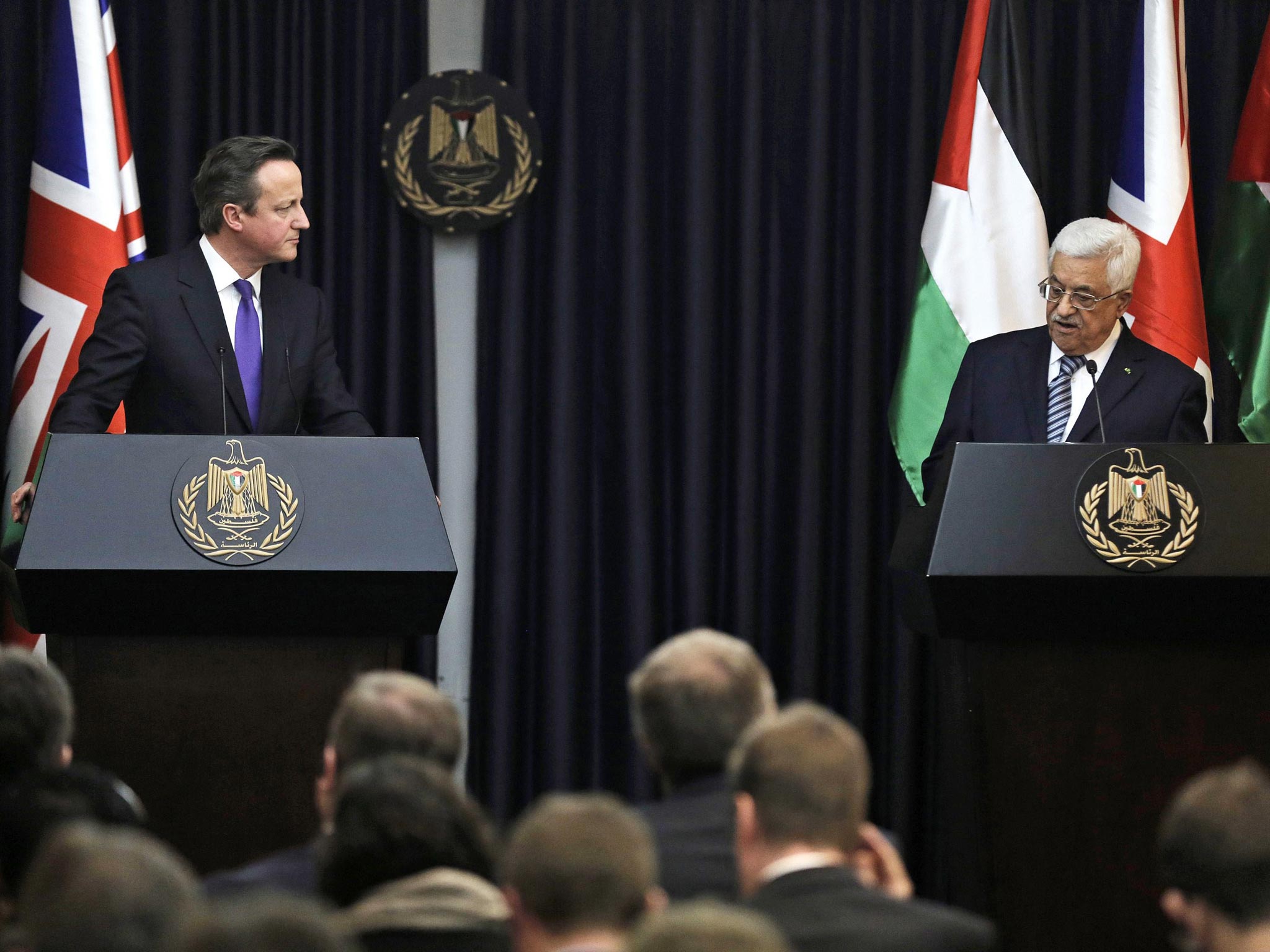 British Prime Minister David Cameron listens to Palestinian President Mahmoud Abbas speak during their joint news conference in the West Bank town of Bethlehem