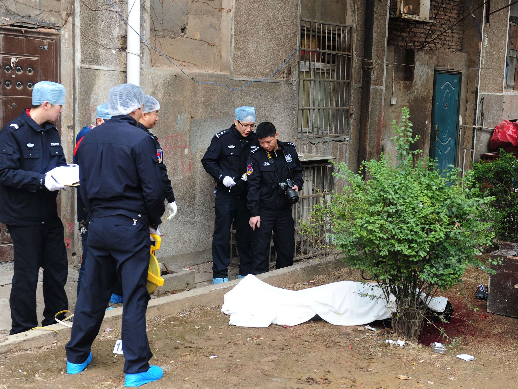 Investigators work at the crime scene near a victim's body (C) where attackers armed with knives killed five people in Changsha, central China's Hunan province on March 14, 2014.