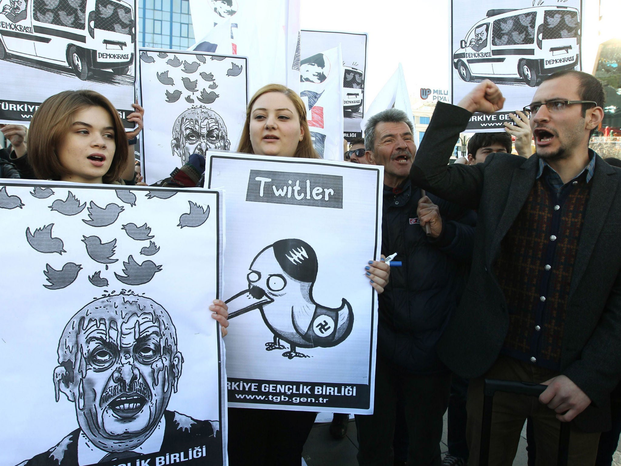 People hold placards as they protest against Turkey's Prime Minister Tayyip Erdogan after the government blocked access to Twitter