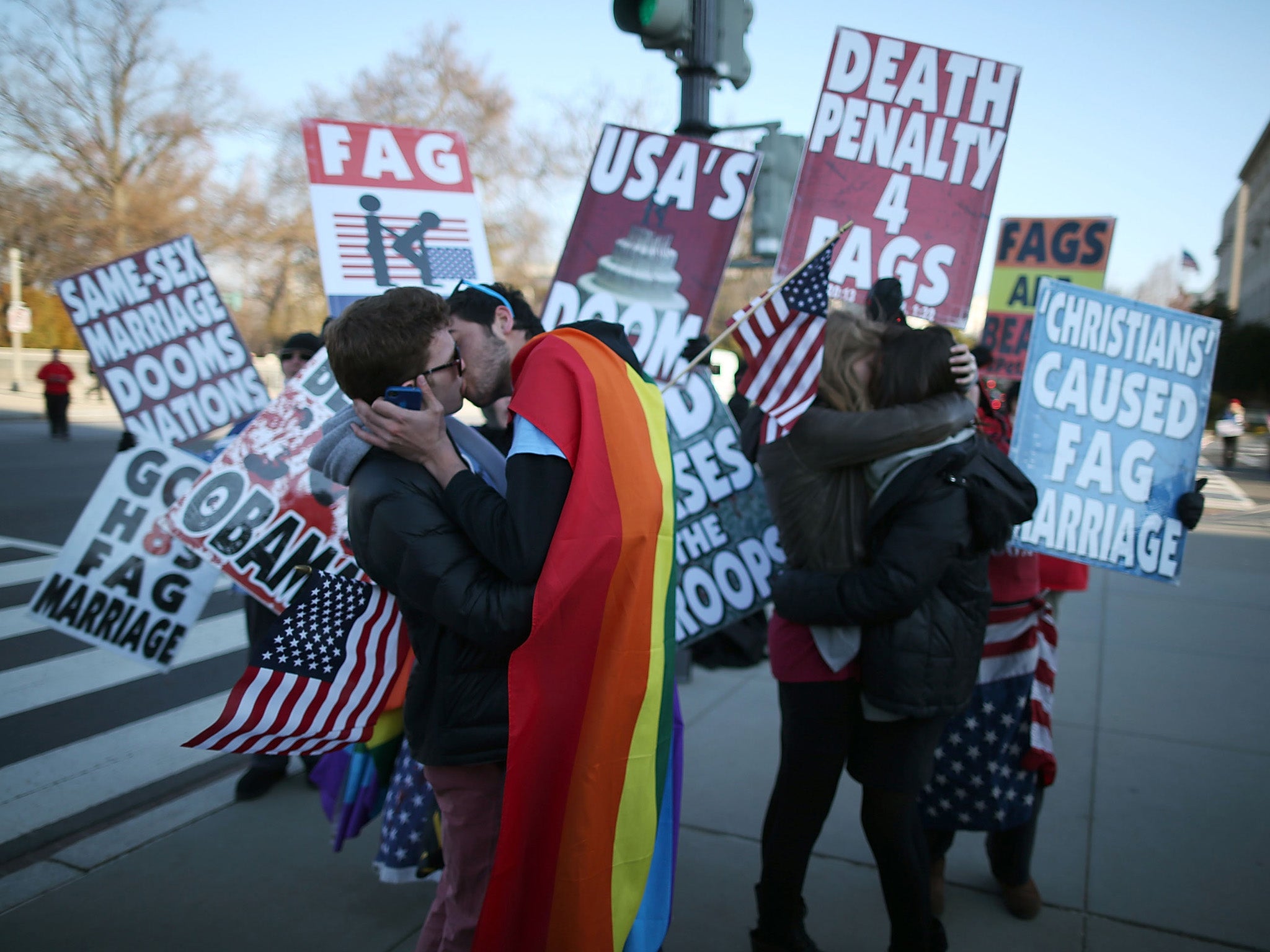 Two same sex couples kiss in front of Westboro Baptist Church protesters at the US Supreme Court. The high court was hearing arguments on whether Congress can withhold federal benefits from legally wed gay couples by defining marriage as only between a ma