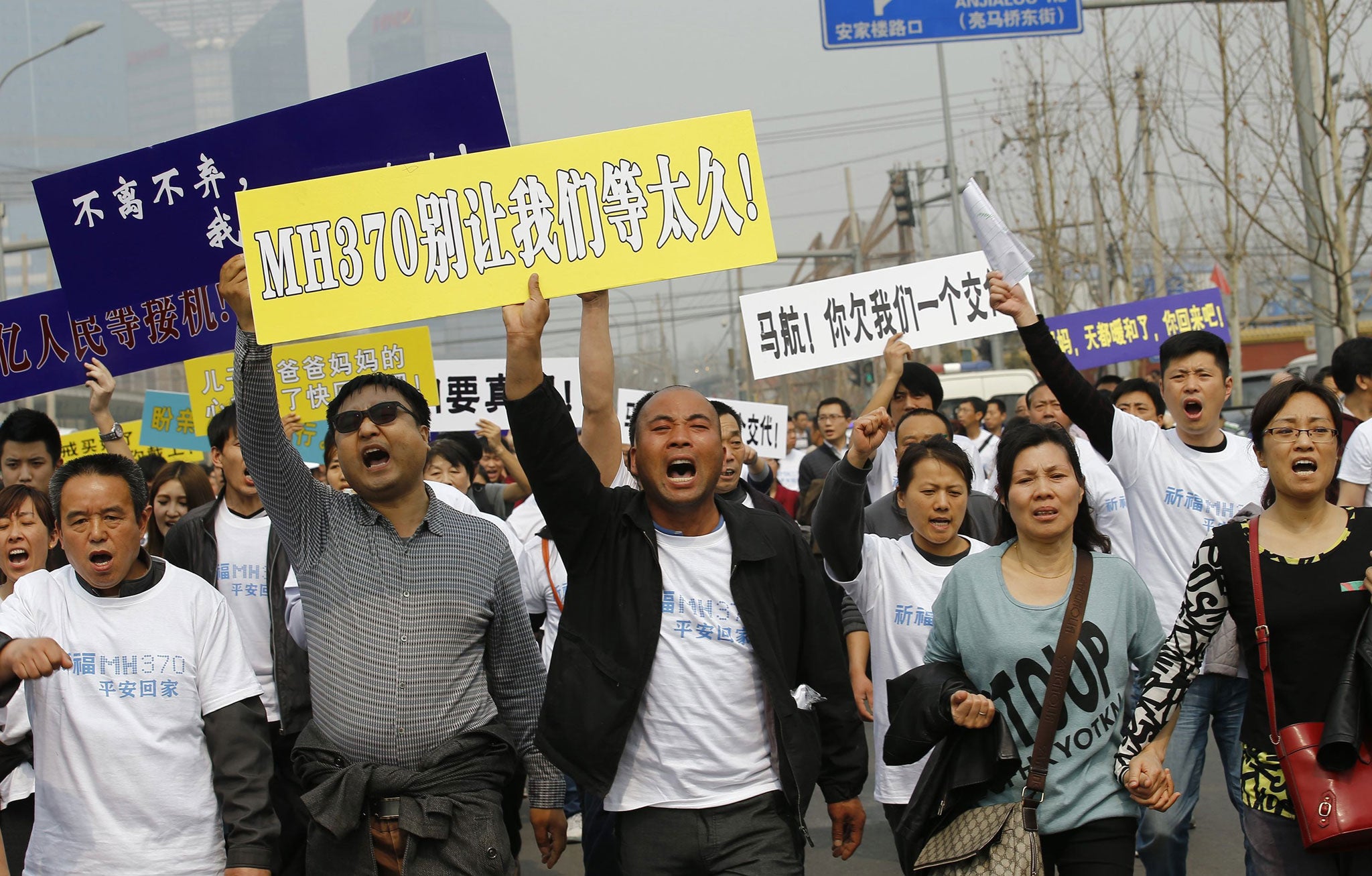 Family members of passengers aboard Malaysia Airlines MH370 shout slogans as they march toward the Malaysian embassy in Beijing