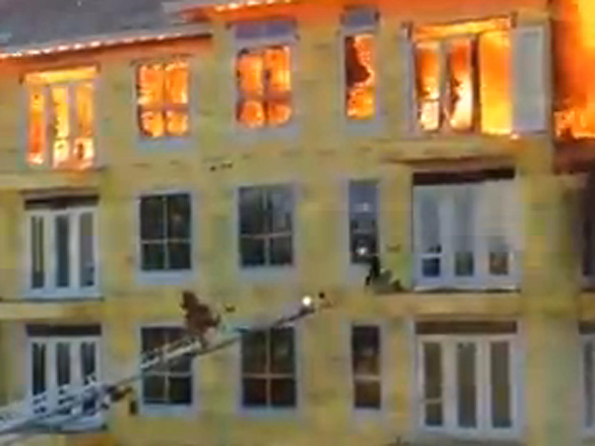 A ladder from an emergency vehicle reaches out to rescue the man from the window ledge