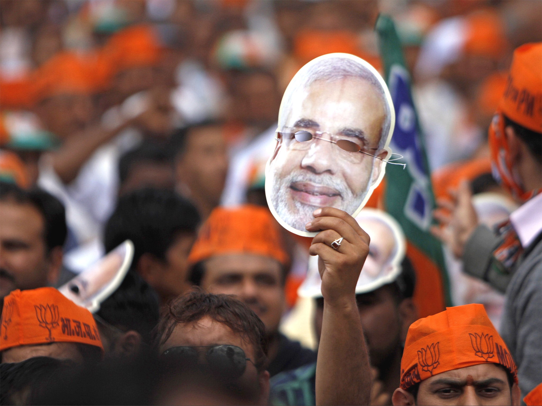 A Bharatiya Janata Party supporter holds high a mask of their prime ministerial candidate Narendra Modi