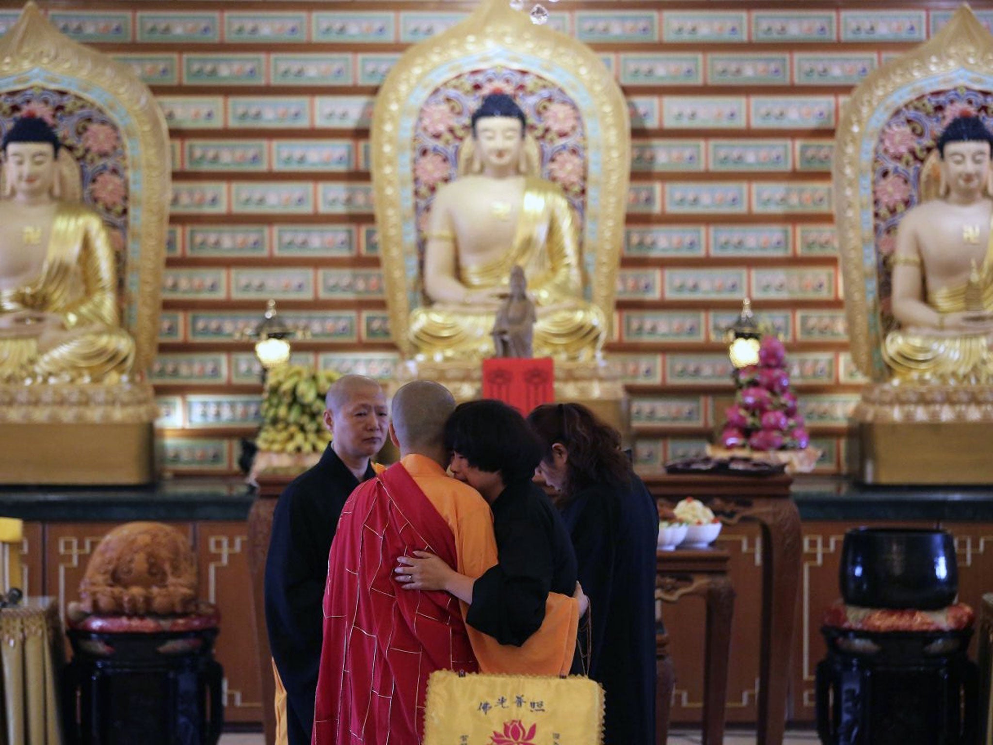 A Chinese relative of passengers on board the missing Malaysia Airlines Flight MH370 is comforted by a monk as she breaks into tears following prayers at a Buddhist temple in Petaling Jaya, Malaysia, Monday March 31, 2014. Relatives from China are in the