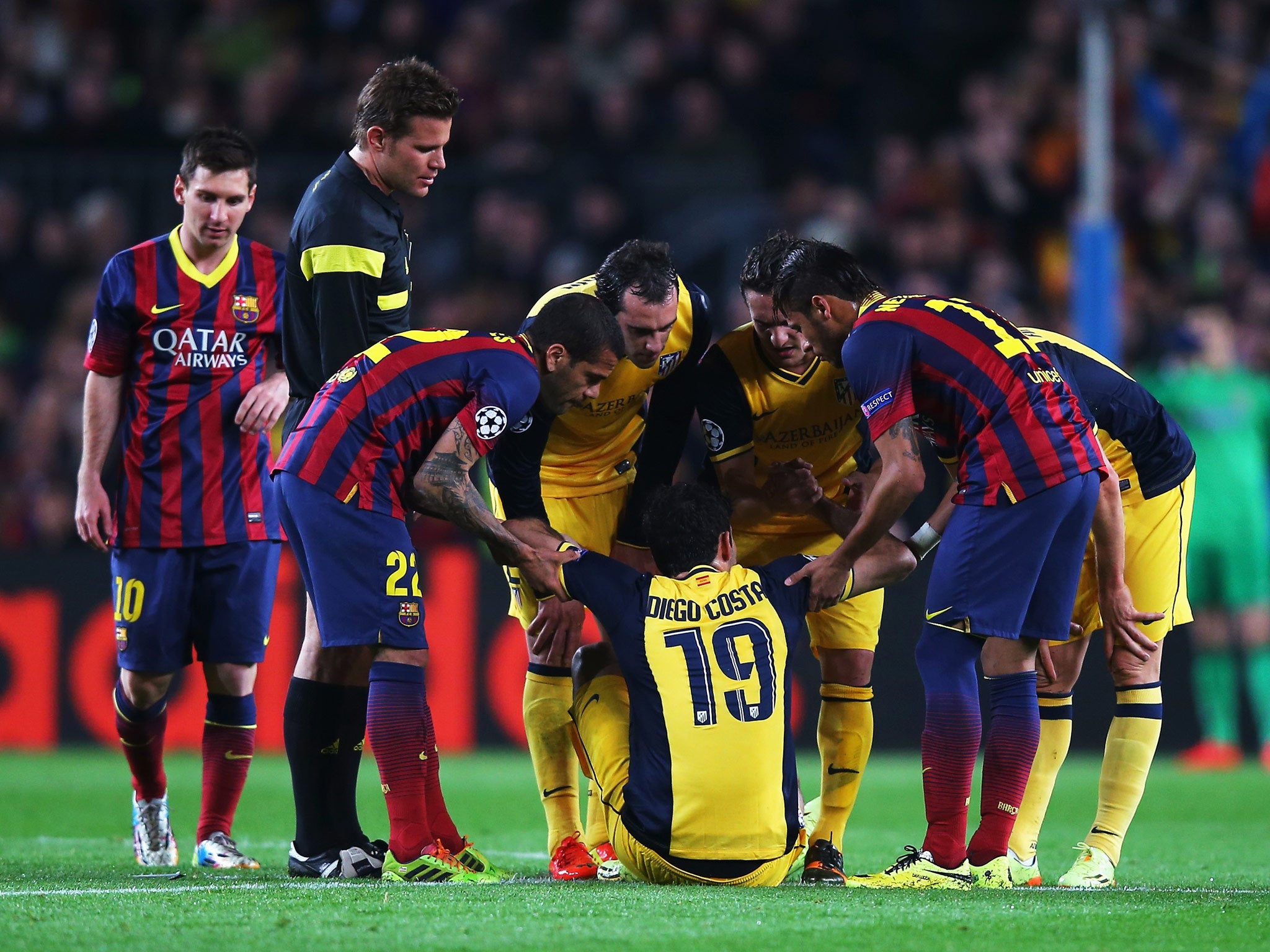 Diego Costa of Atletico Madrid is helped to his feet before leaving the field injured in the Champions League quarter-final against Barcelona