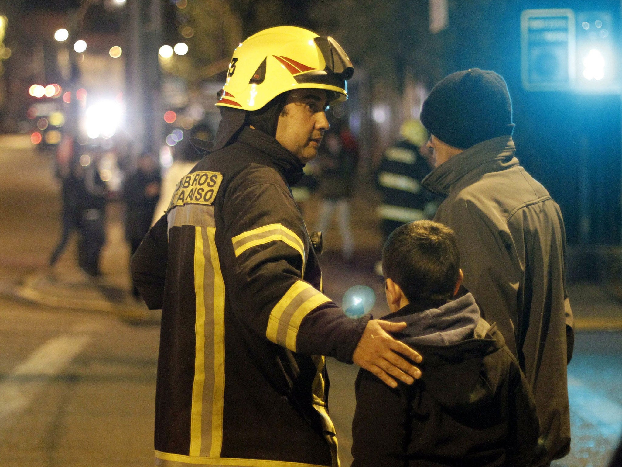 Firemen help in the evacuation of people towards a high zone due to a Tsunami alert after an 8.2 Richter scale earthquake in Valaparaiso