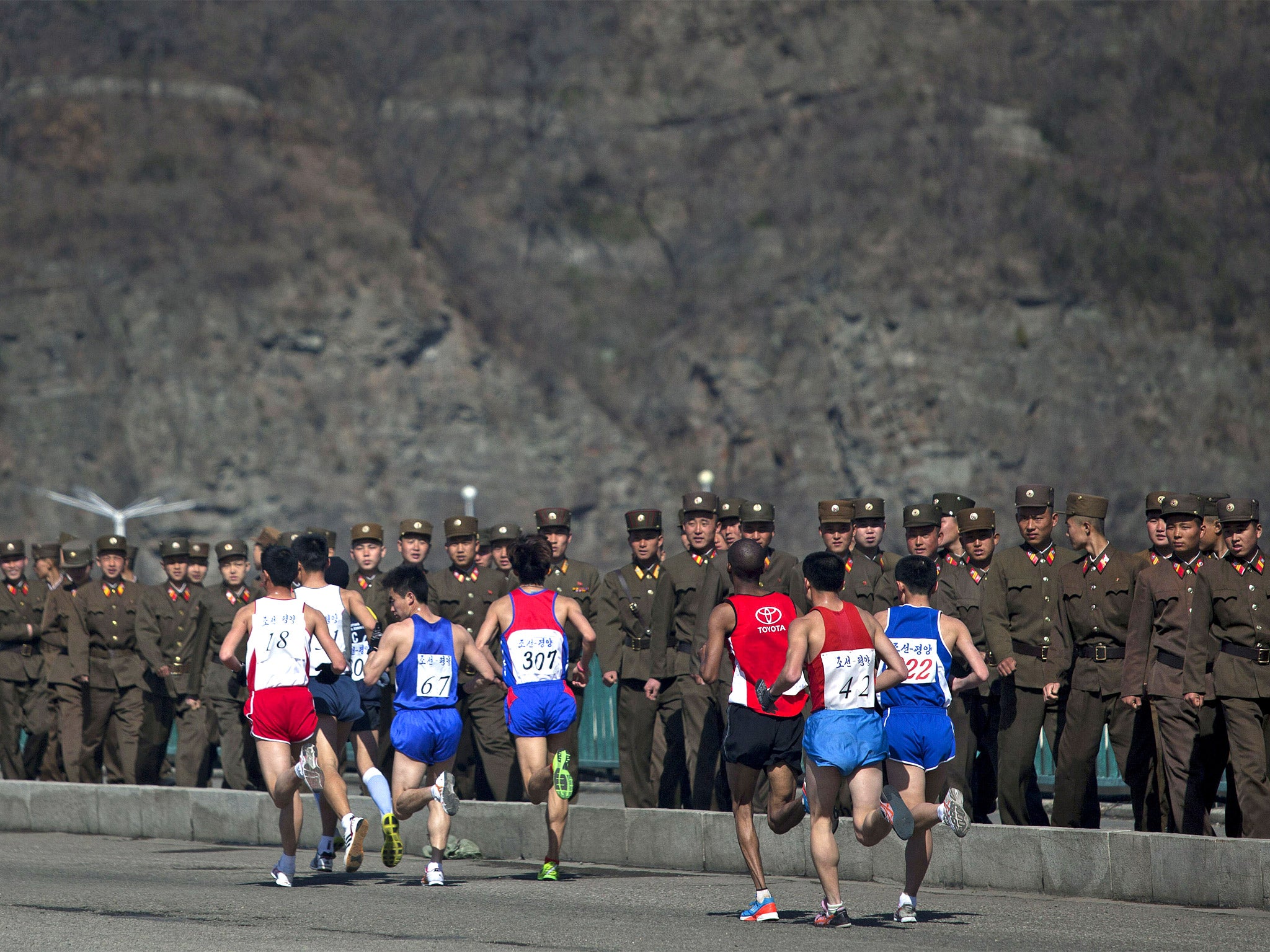 Marathon runners pass by a long row of North Korean soldiers as they cross a bridge in Pyongyang during last year's race