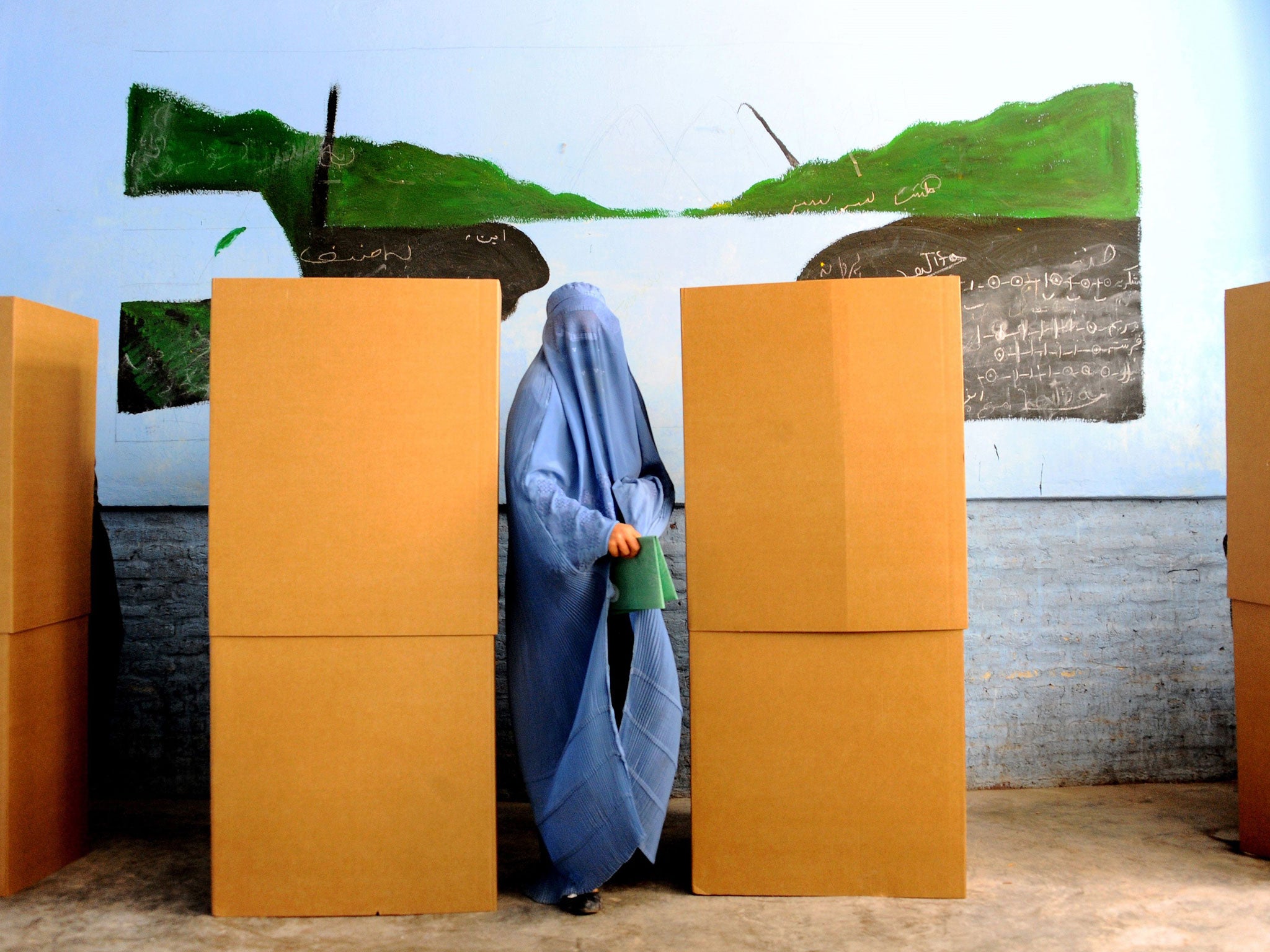 An Afghan woman shows her inked finger after voting at a polling station in the northwestern city of Herat