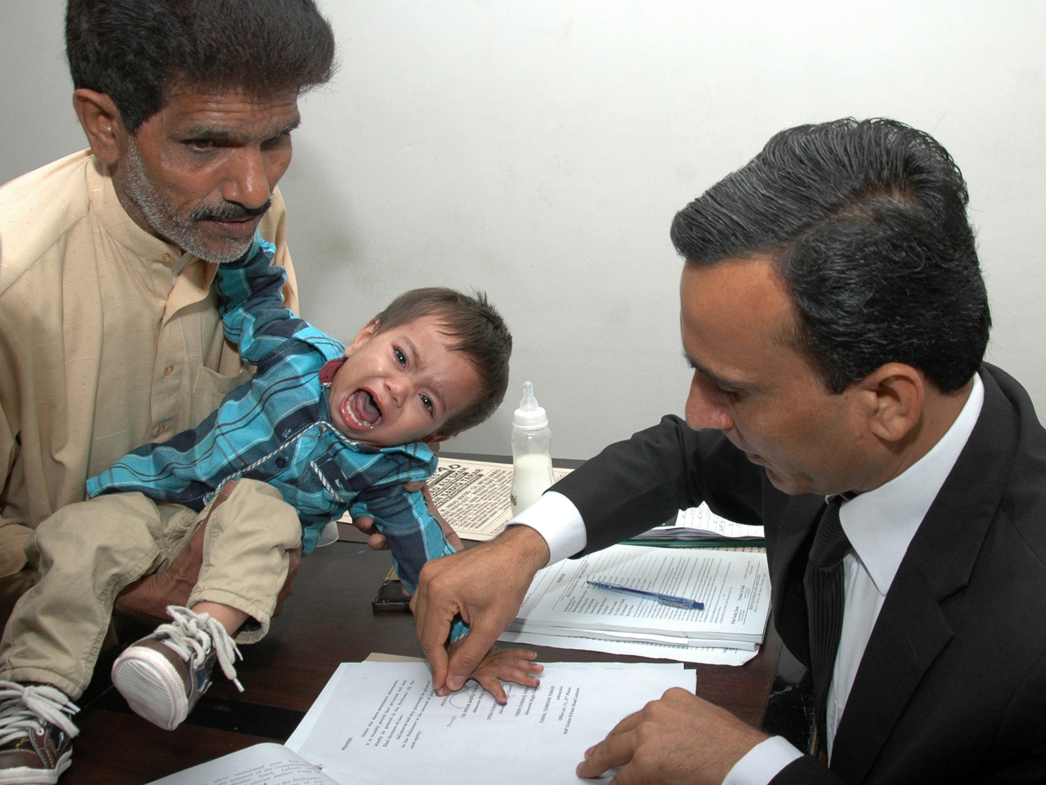 Nine-month-old Muhammad Mosa Khan has his finger prints taken by an official in court