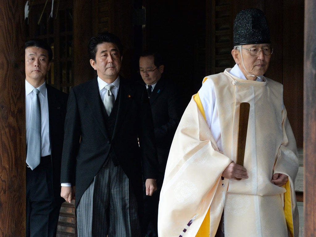 A Shinto priest (R) leads Japanese Prime Minister Shinzo Abe (C) as he visits the controversial Yasukuni war shrine in Tokyo on December 26, 2013, in a move Beijing condemned as 'absolutely unacceptable'. Abe described his visit, which is certain to roil