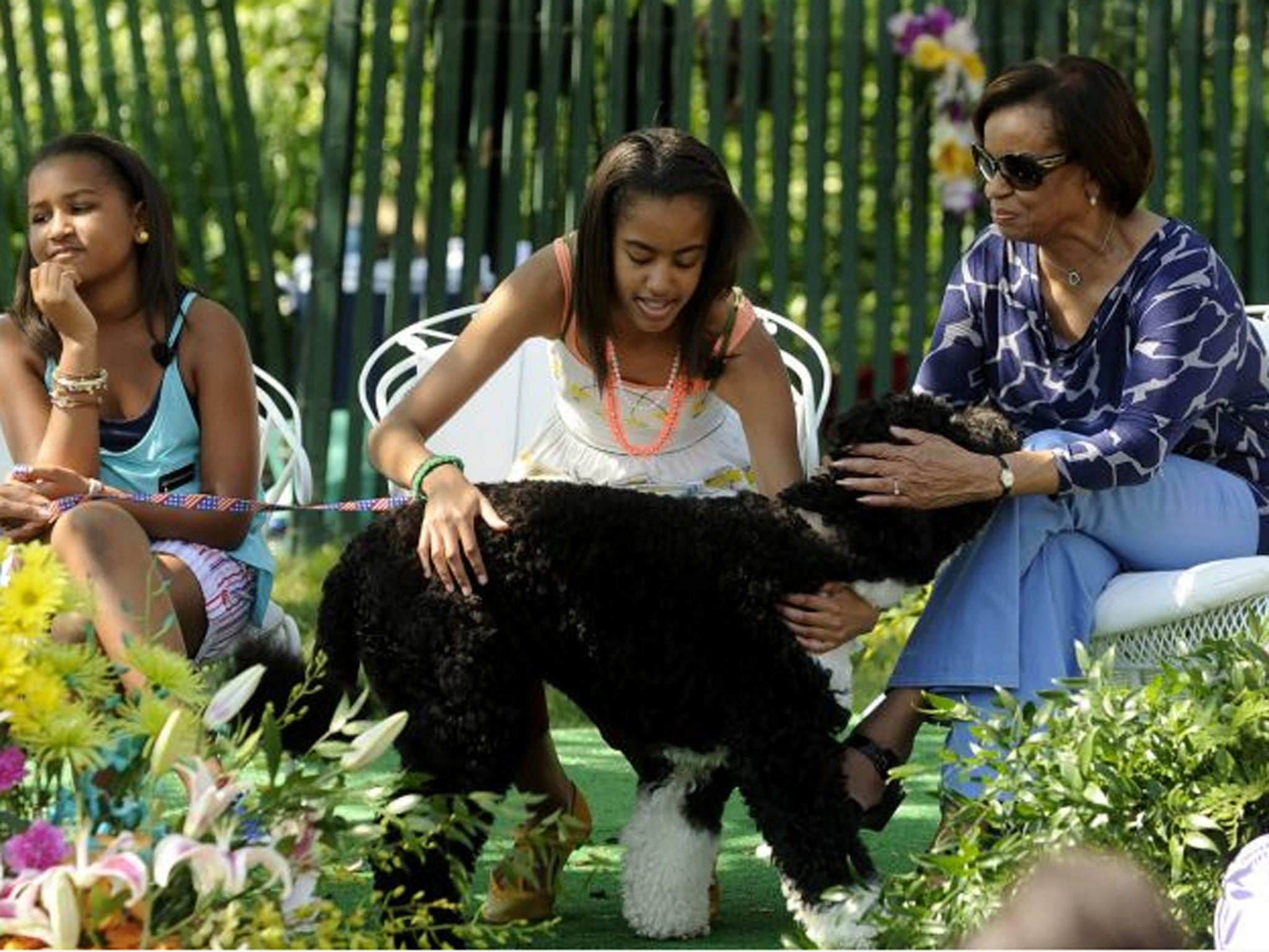 The Obamas' daughters Sasha and Malia and Michele's mother Marian Robinson play with their dog Bo during the White House Easter Egg Roll on the South Lawn of the White House