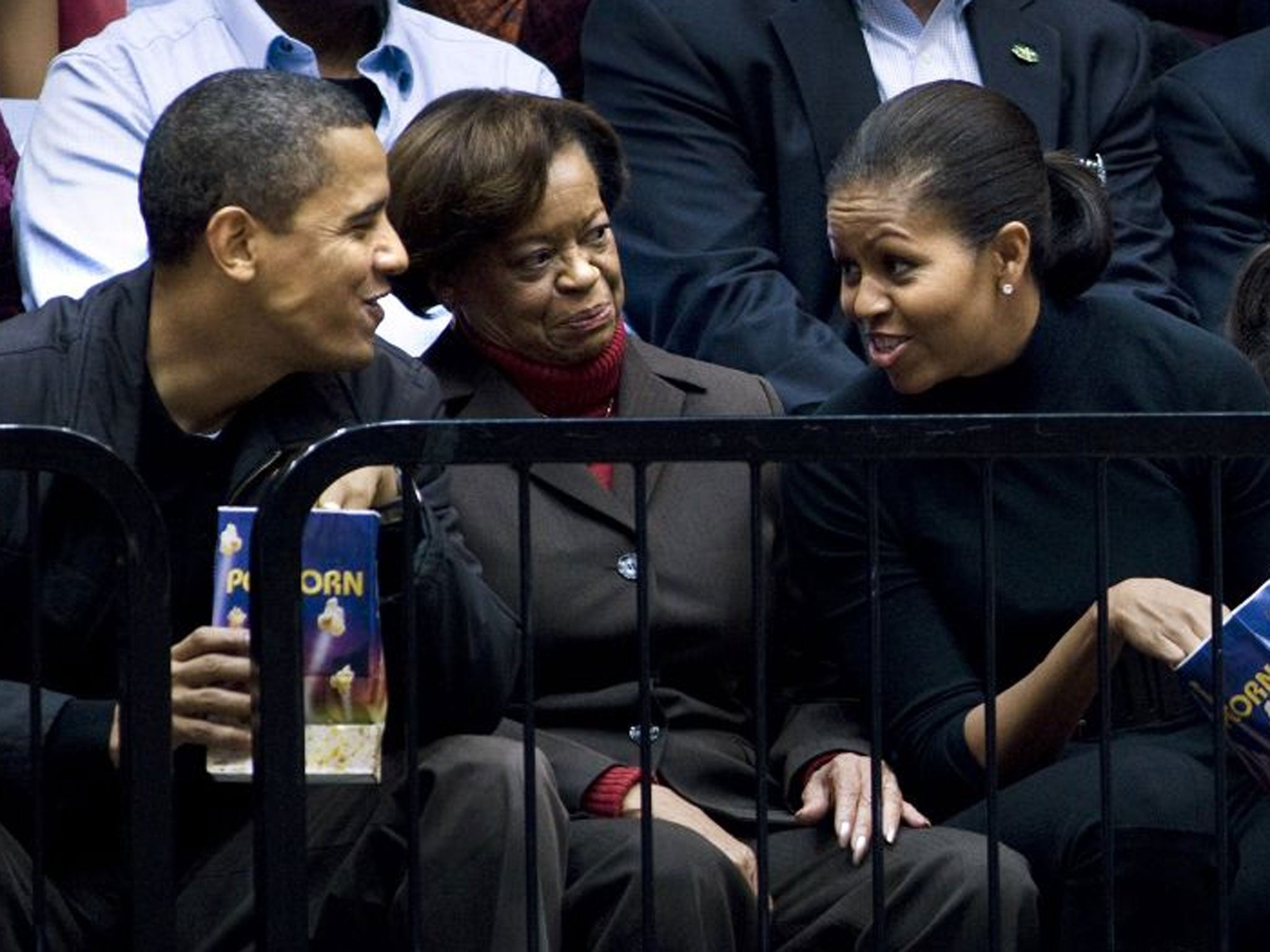 President Barack Obama speaks with his mother in law Marian Robinson (C) and wife first lady Michelle Obama (R) during a college basketball game at George Washington University in 2010