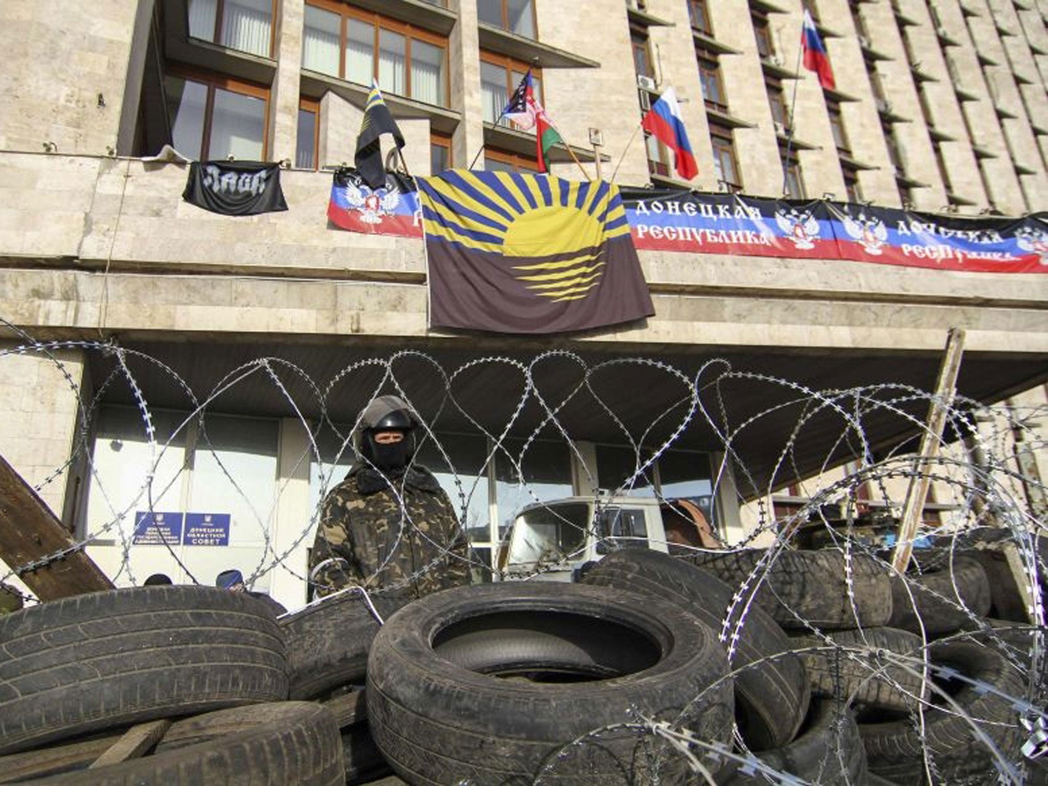 A pro-Russian protester stands behind a barricade erected in front of the seized regional government building in Donetsk 7 April, 2014.