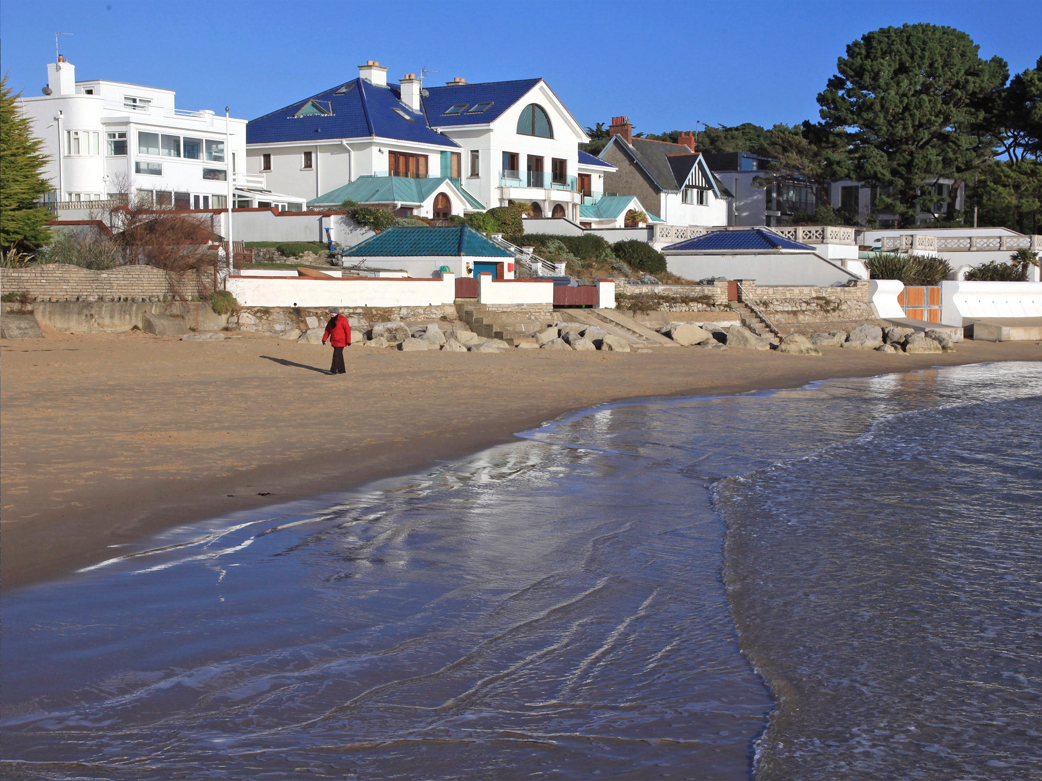 A person walks along the beach in Sandbanks