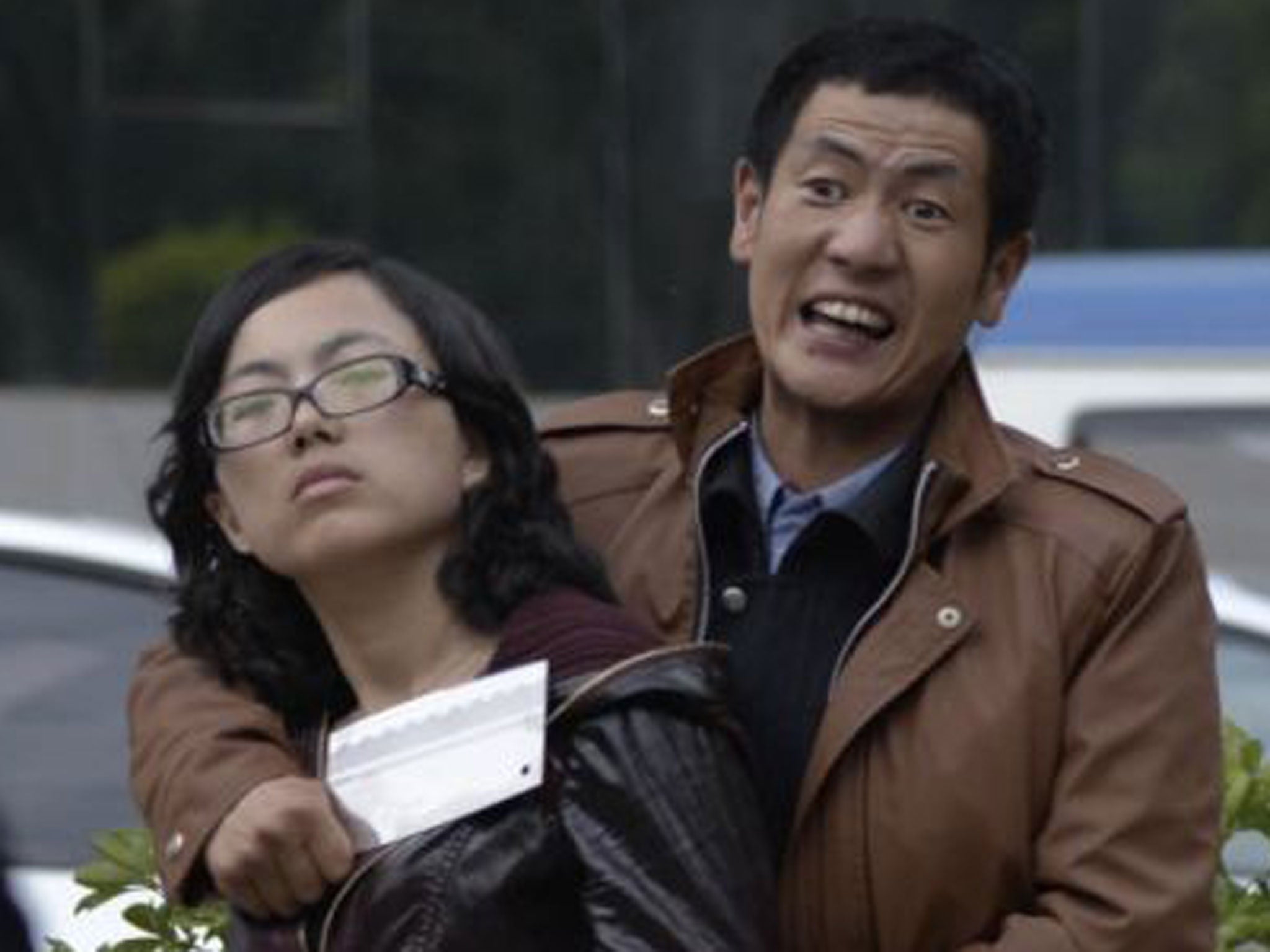 A man shouts at police officers as he holds a woman hostage with a cleaver on a street in Kunming, Yunnan province