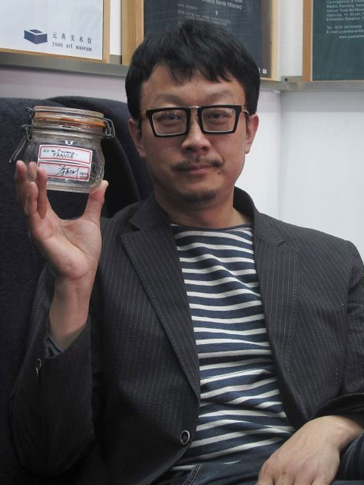 Beijing artist Liang Kegang poses with the jar of fresh air collected in Provence, France, in an art gallery in Beijing, China.