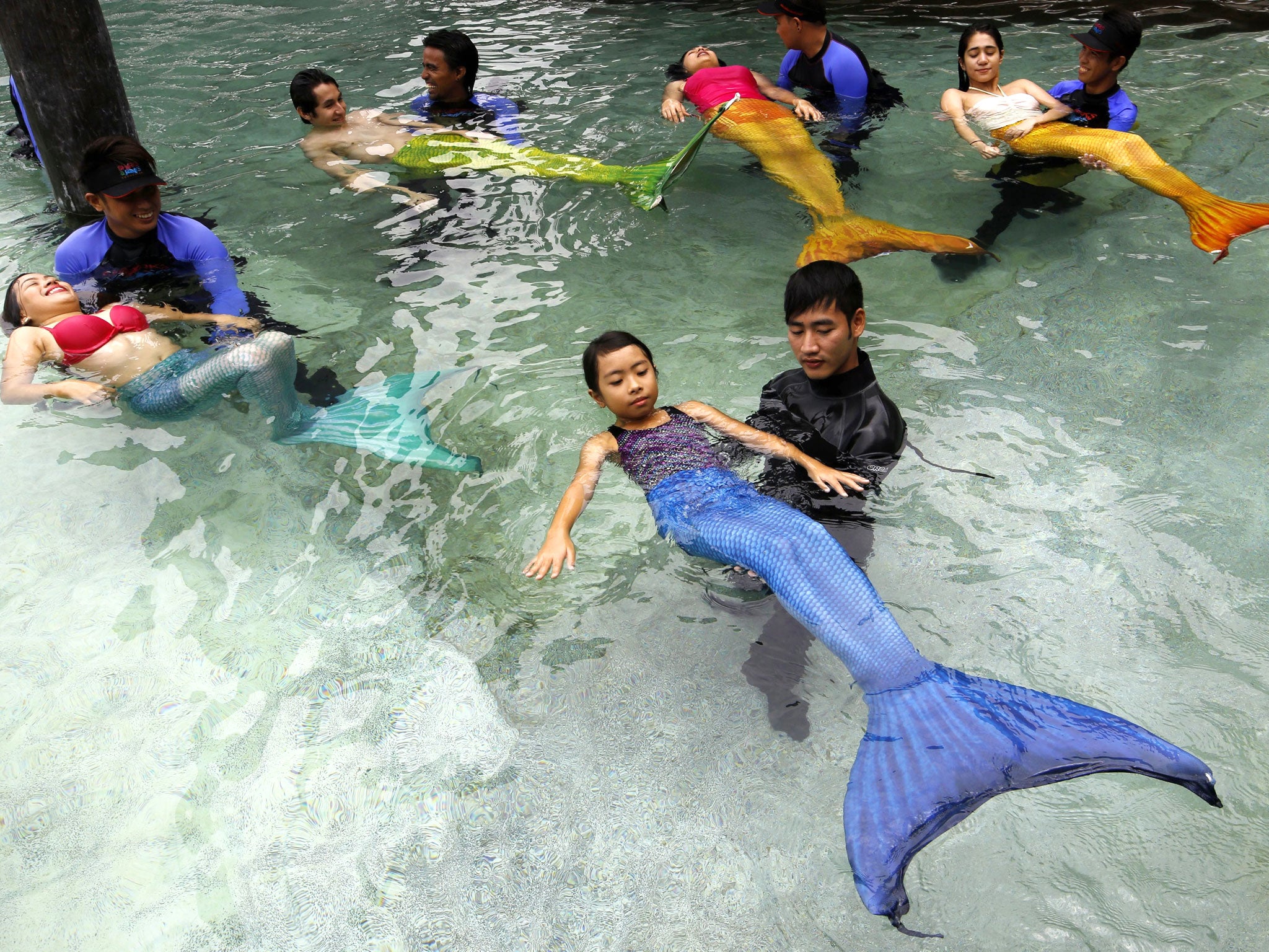 Filipino instructors teach participants how to swim like mermaids during the 'Mermaid Swim Experience' at Manila Ocean Park