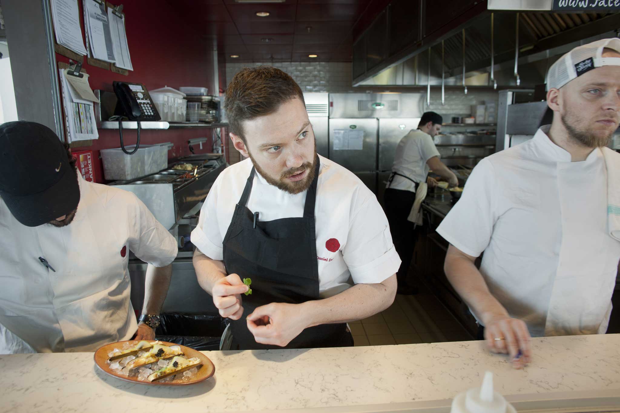 12am: head chef Dan O'Doherty (centre) prepares steamed razor clams from the raw bar