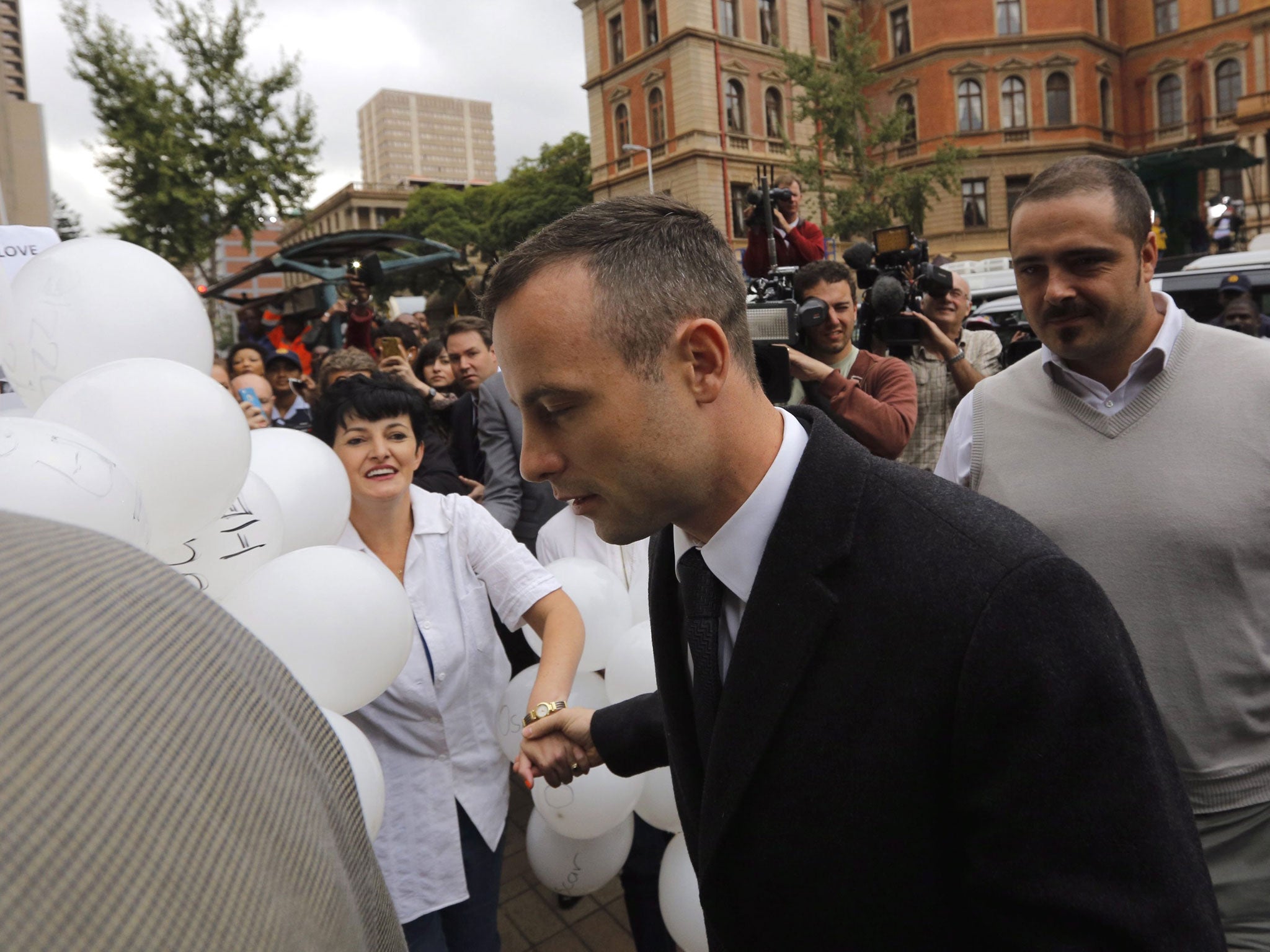 Oscar Pistorius holds hand of his supporter as he arrives at court in Pretoria