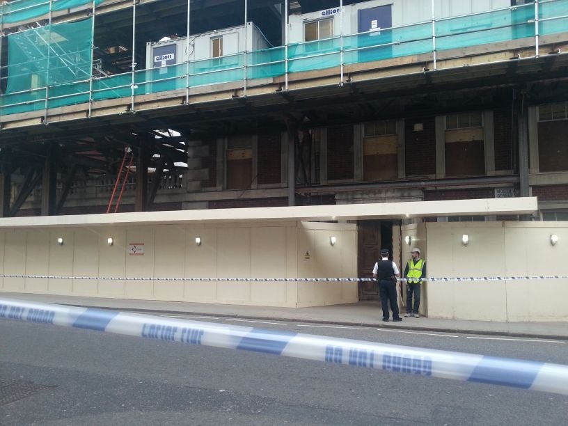 A police officer talks with a construction worker at the scene of partial building collapse in Grosvenor Square in Mayfair, central London.