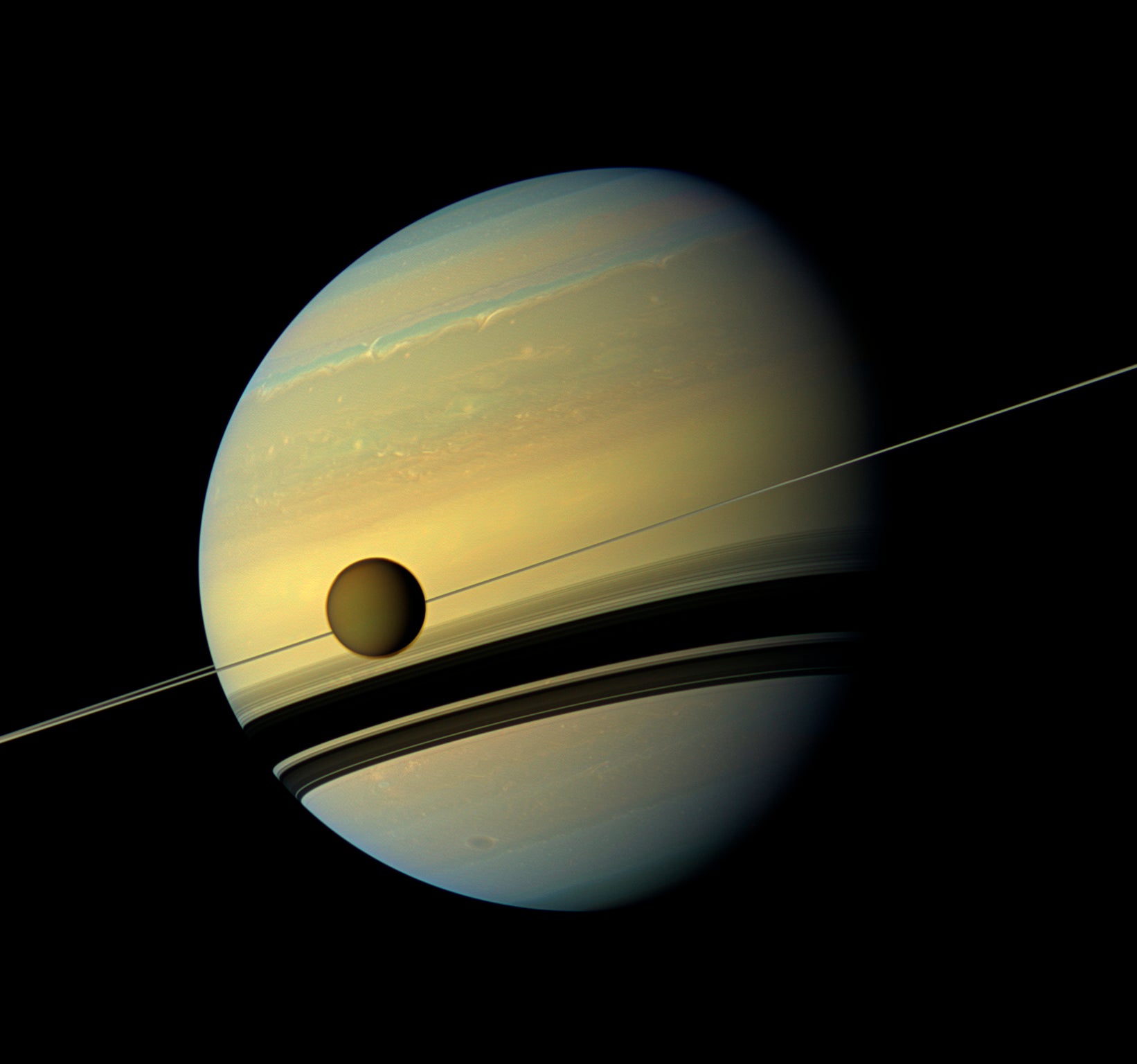 Titan, Saturn's largest moon appears before the planet as it undergoes seasonal changes. The moon measures 3,200 miles, or 5,150 kilometers, across and is larger than the planet Mercury. Cassini scientists have been watching the moon's south pole since a vortex appeared in its atmosphere in 2012.