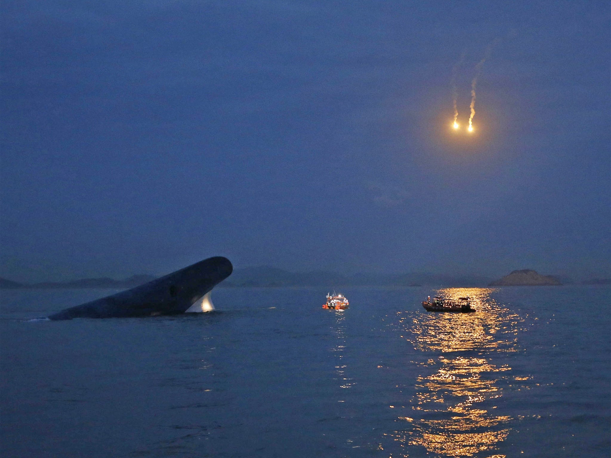 South Korean ferry 'Sewol' is seen sinking in the sea off Jindo, as lighting flares are released for a night search