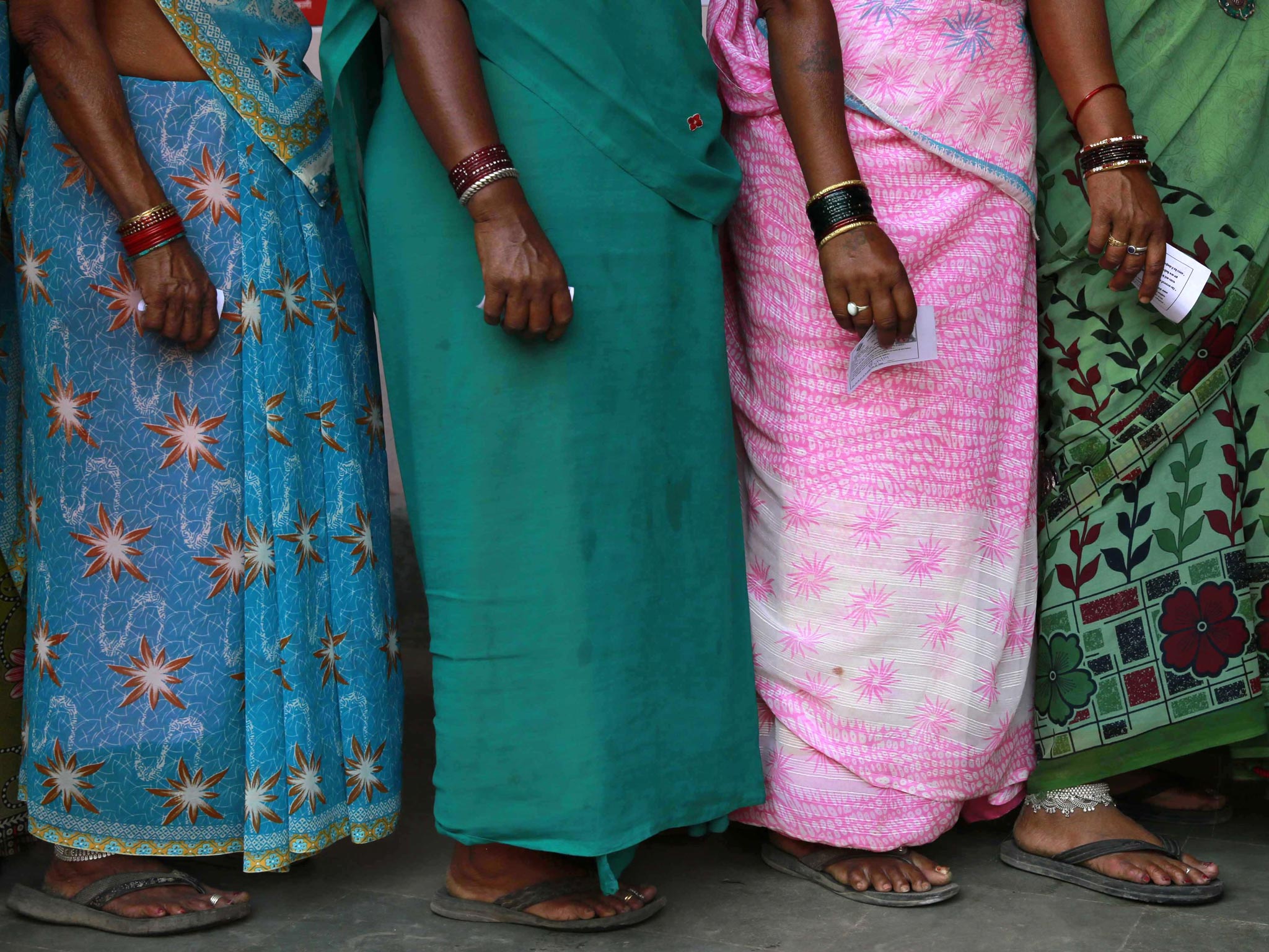 Indian women stand in a queue to cast their votes in Rajnandgaon, India