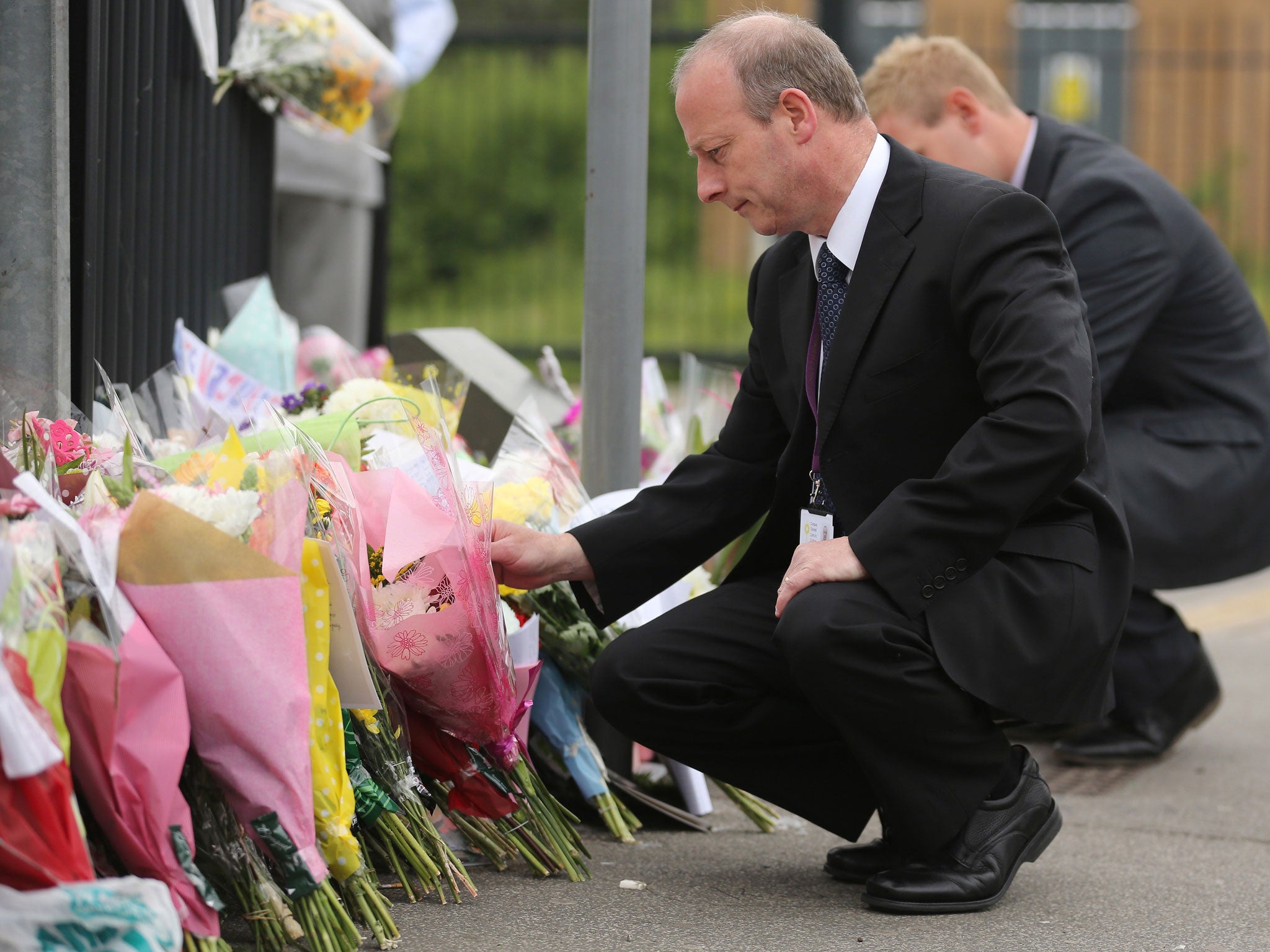 Keiran Sykes, the deputy headteacher of Corpus Christi Catholic College, reads the hundreds of tributes left in honour of slain teacher Ann Maguire in Leeds