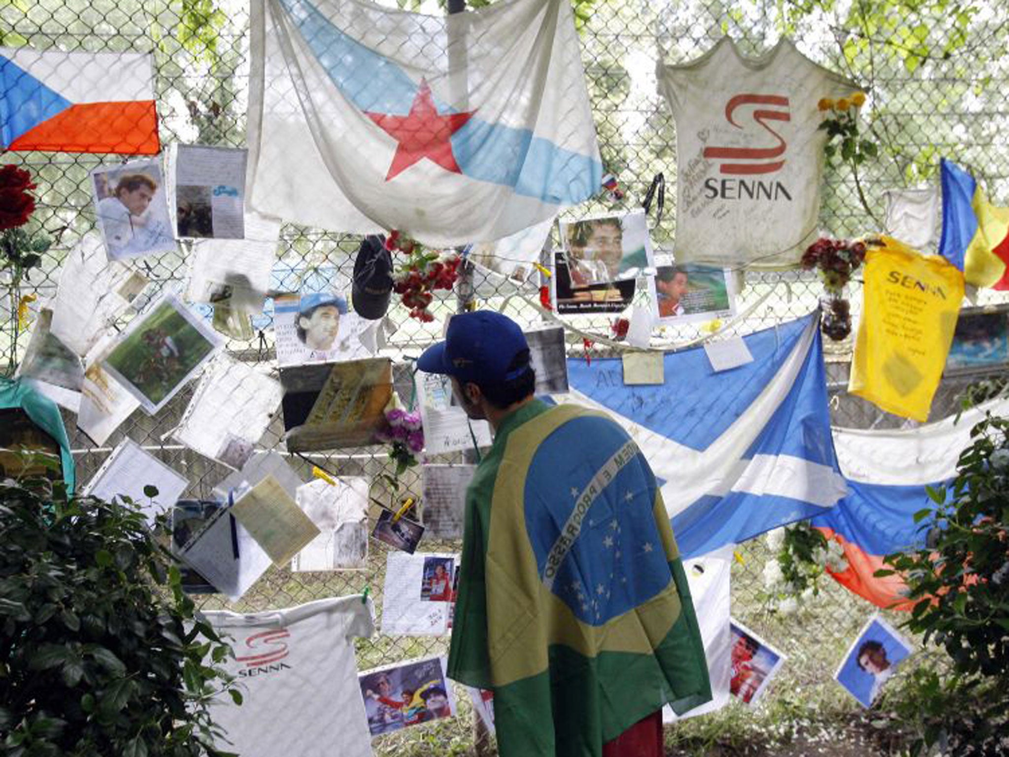 A fan of Brazilian Formula One driver Ayrton Senna reads handwritten notes and messages left at a statue memorial at the Imola race track today