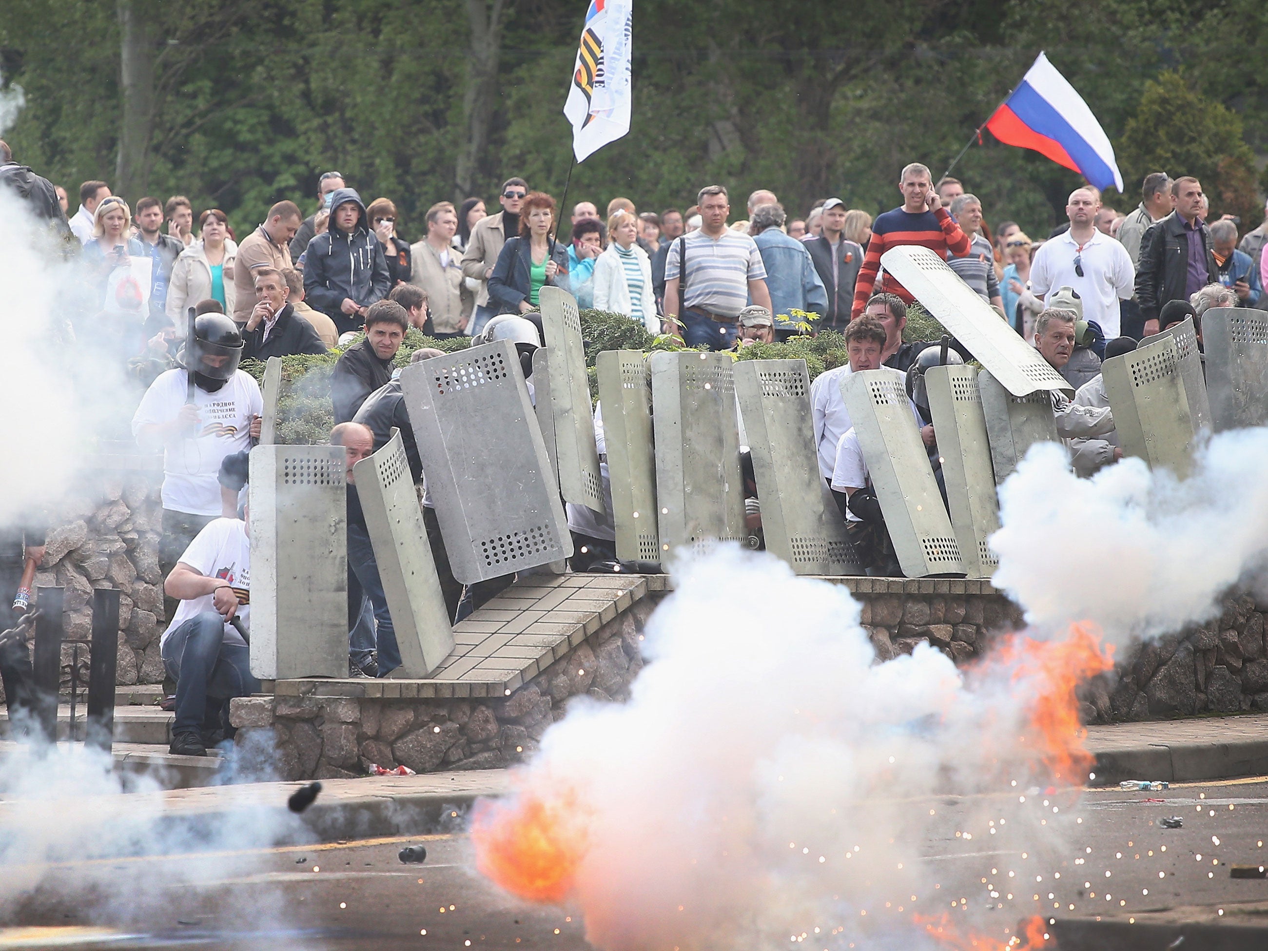 Police officers who retreated into the prosecutors office fire gas and stun grenades at pro-Russian activists who take cover behind shields taken from the police on May 1, 2014 in Donetsk, Ukraine. Activists marched to the prosecutor's office and overran