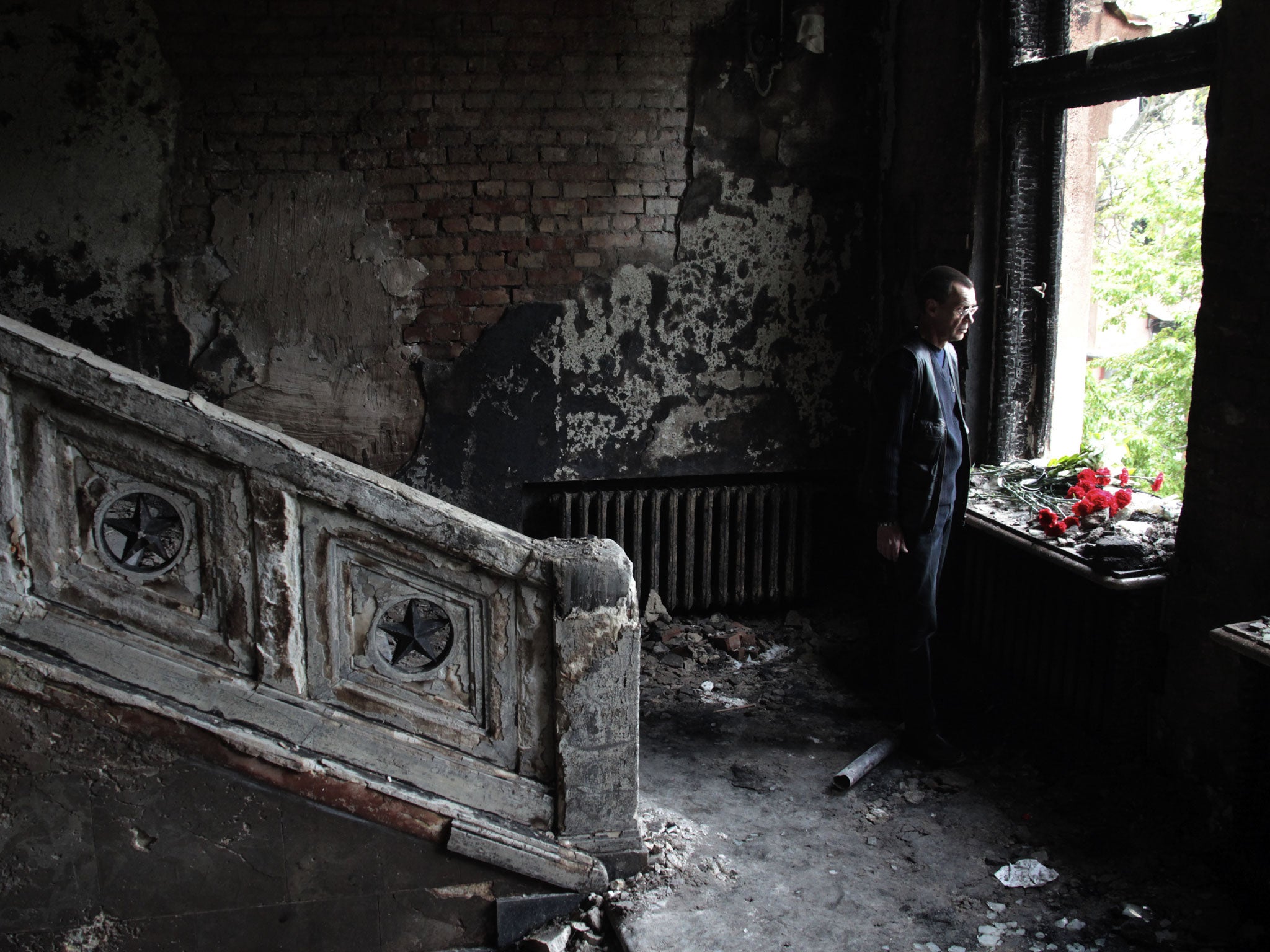 A man lays flowers inside the trade union offices in Odessa, where more than 40 people died – some from gunshot wounds, but most in a fire that tore through the building