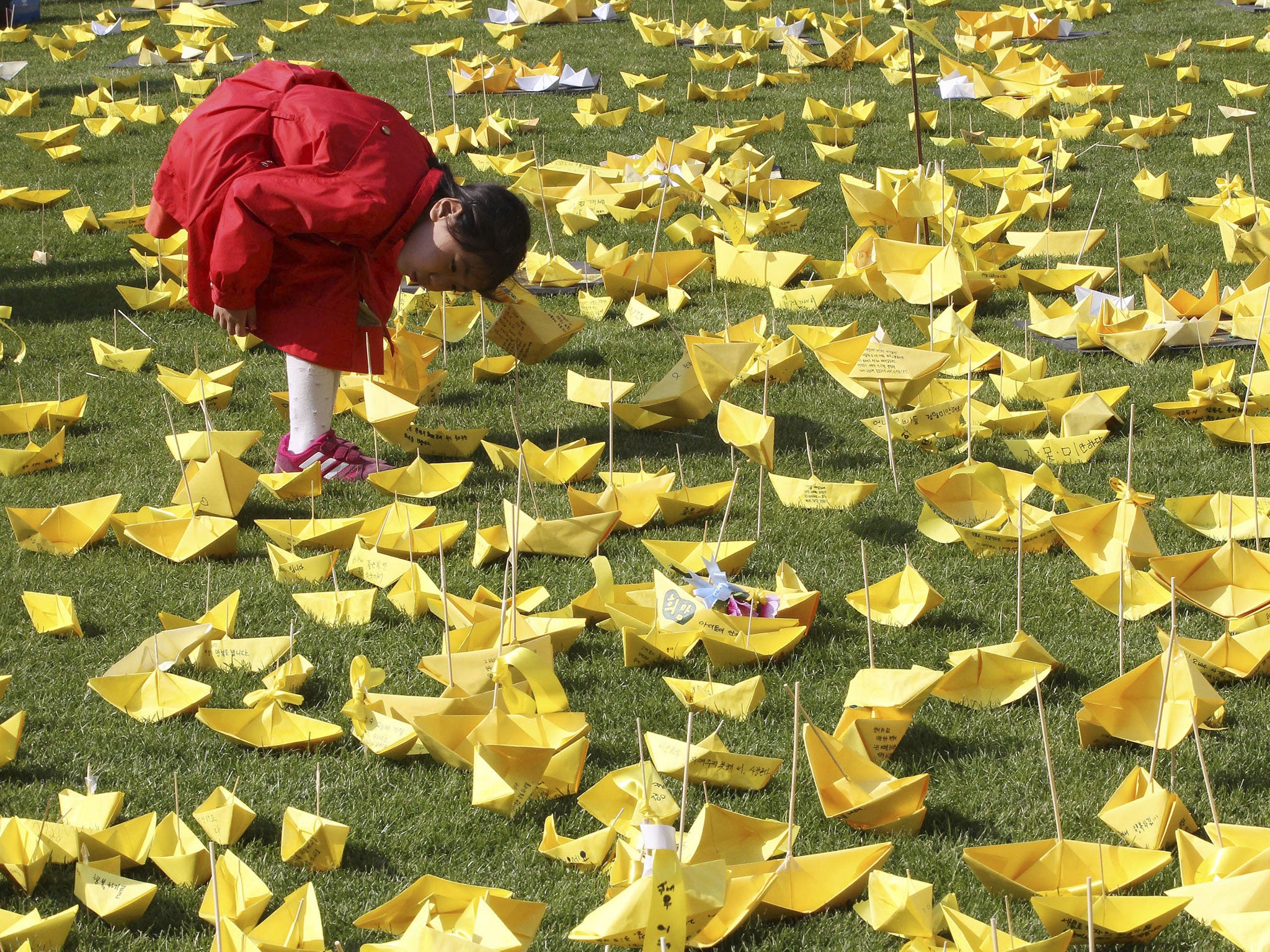 A girl reads massages written on paper ships for the victims of the sunken ferry Sewol at a group memorial altar in Seoul, South Korea