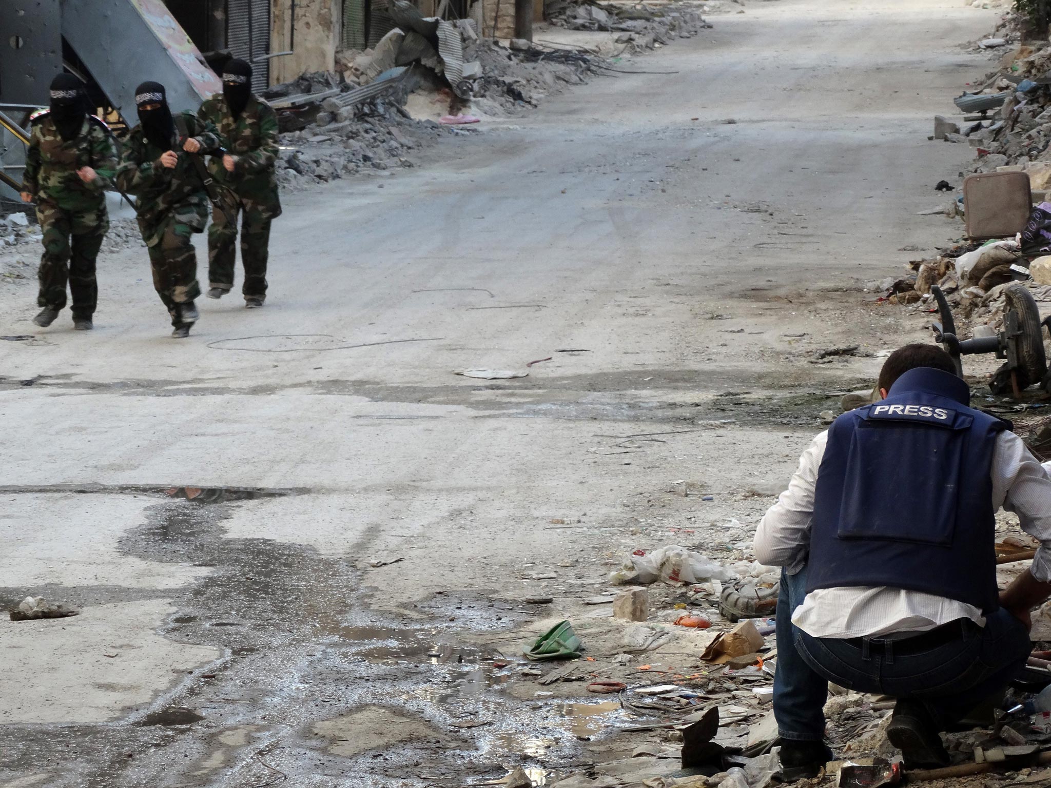 Danger zone: rebel fighters run past a journalist in Aleppo, where being captured is the nightmare of all those reporting on the war