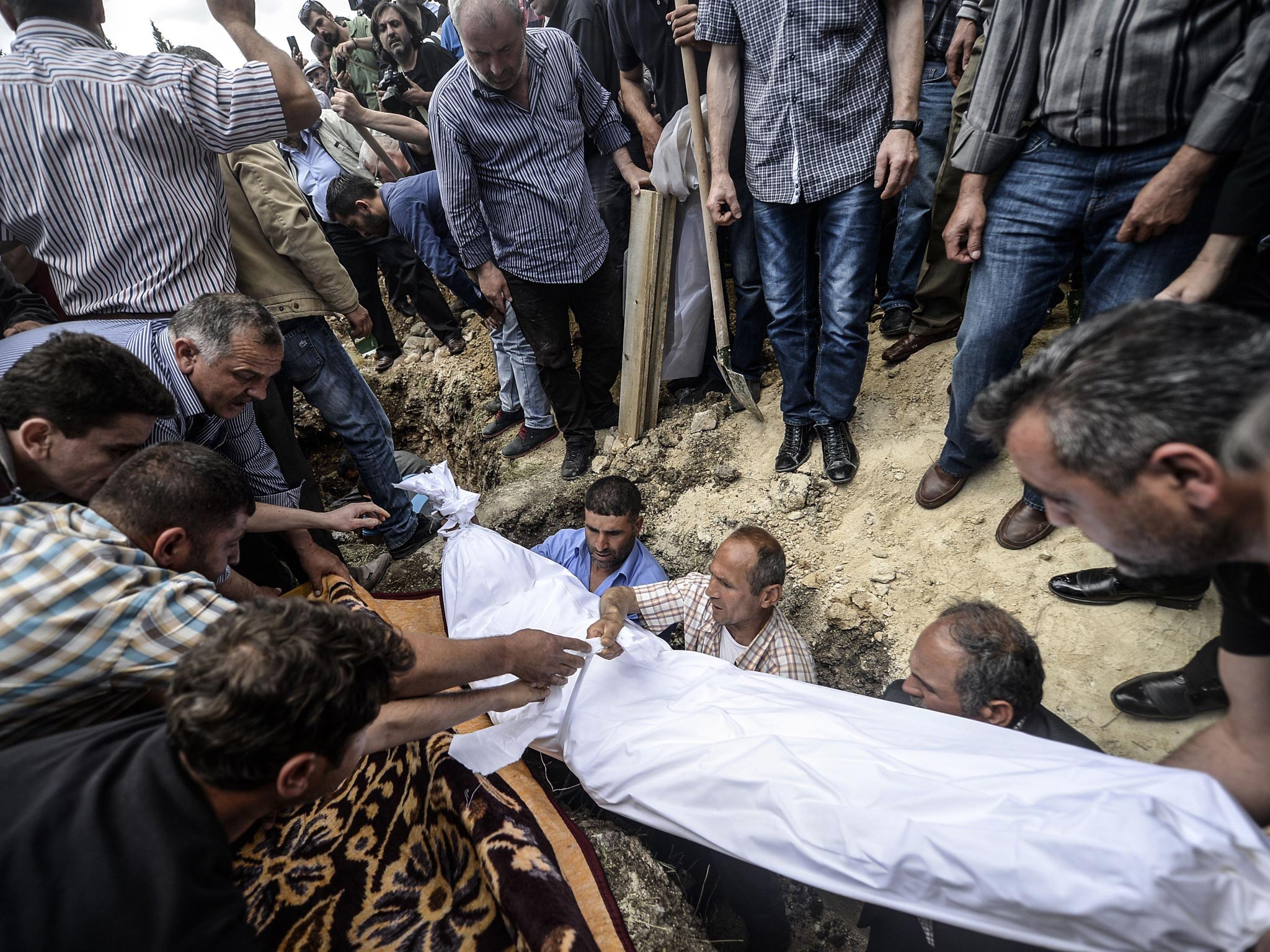 People hold the body of one of the 282 confirmed
dead miners at a funeral yesterday in Soma