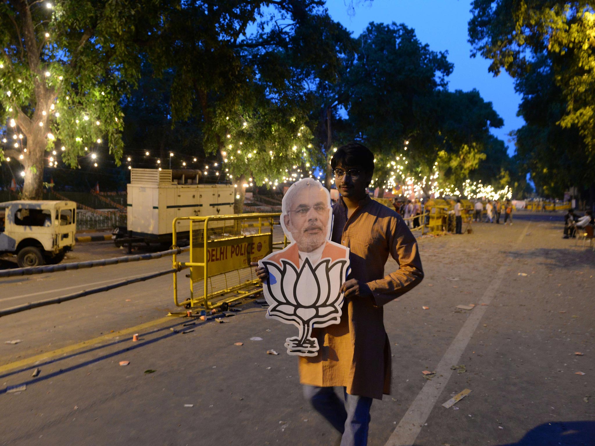 An Indian Bharatiya Janata Party (BJP) supporter hold an cutout of Narinder Modi with the lotus party symbol outside the BJP headquarters in New Delhi