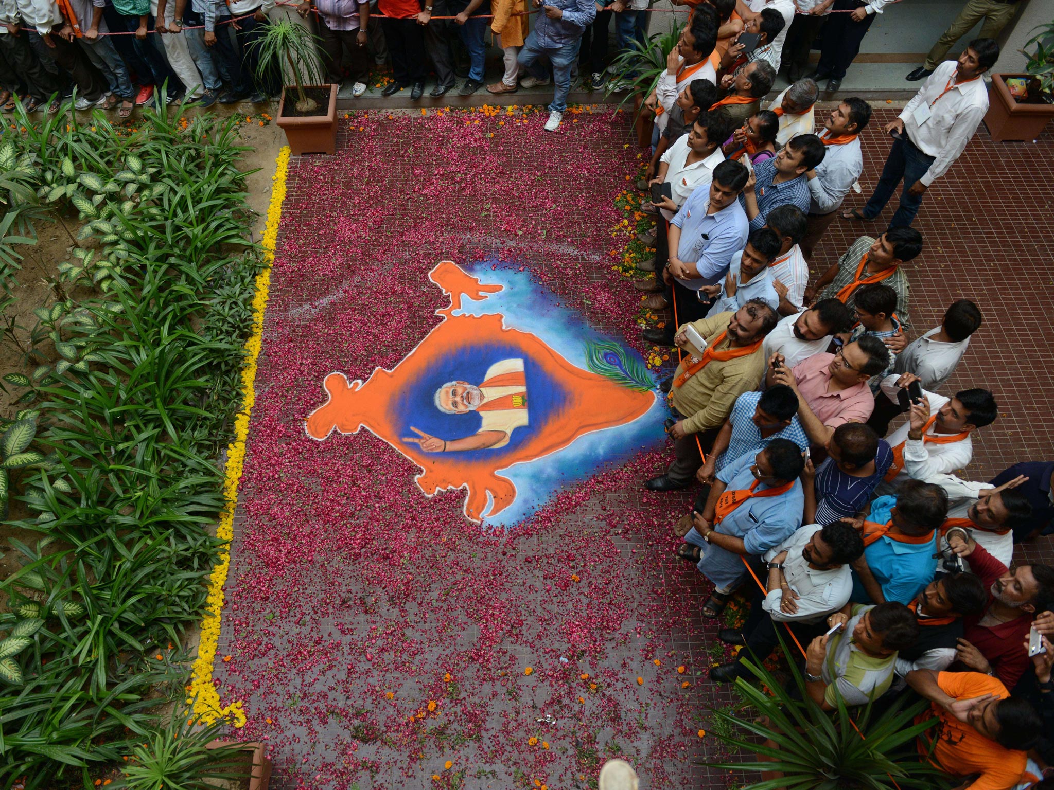 BJP supporters look on near a Rangoli decoration showing a portrait of Narendra Modi