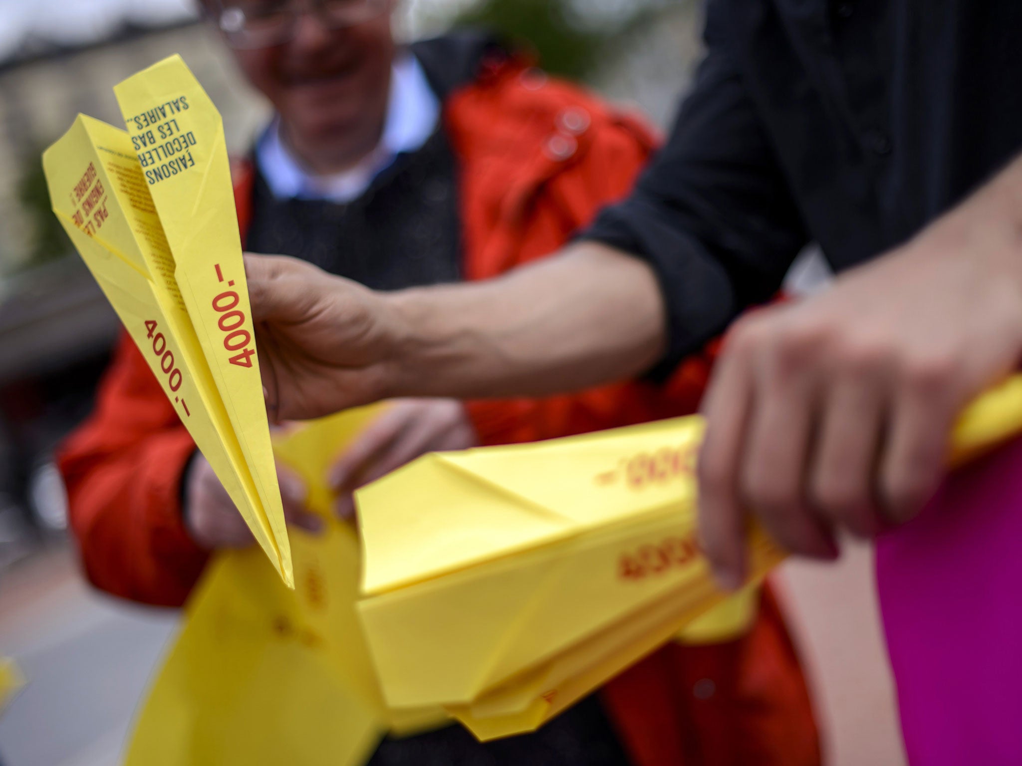 People hold paper planes during an action to support the minimum wage of 4000 Swiss Francs in Geneva.