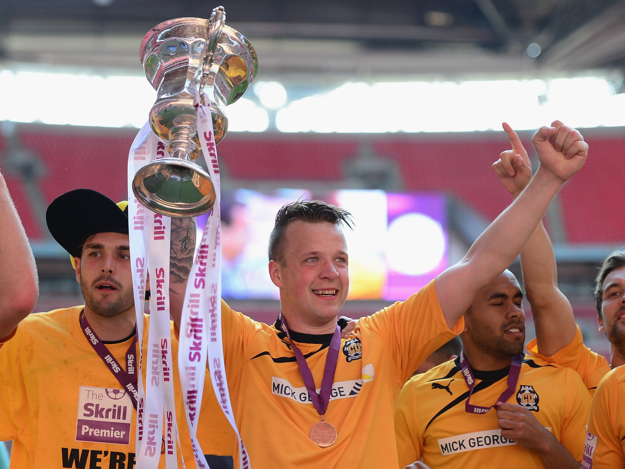 Cambridge players celebrate with the play-off trophy