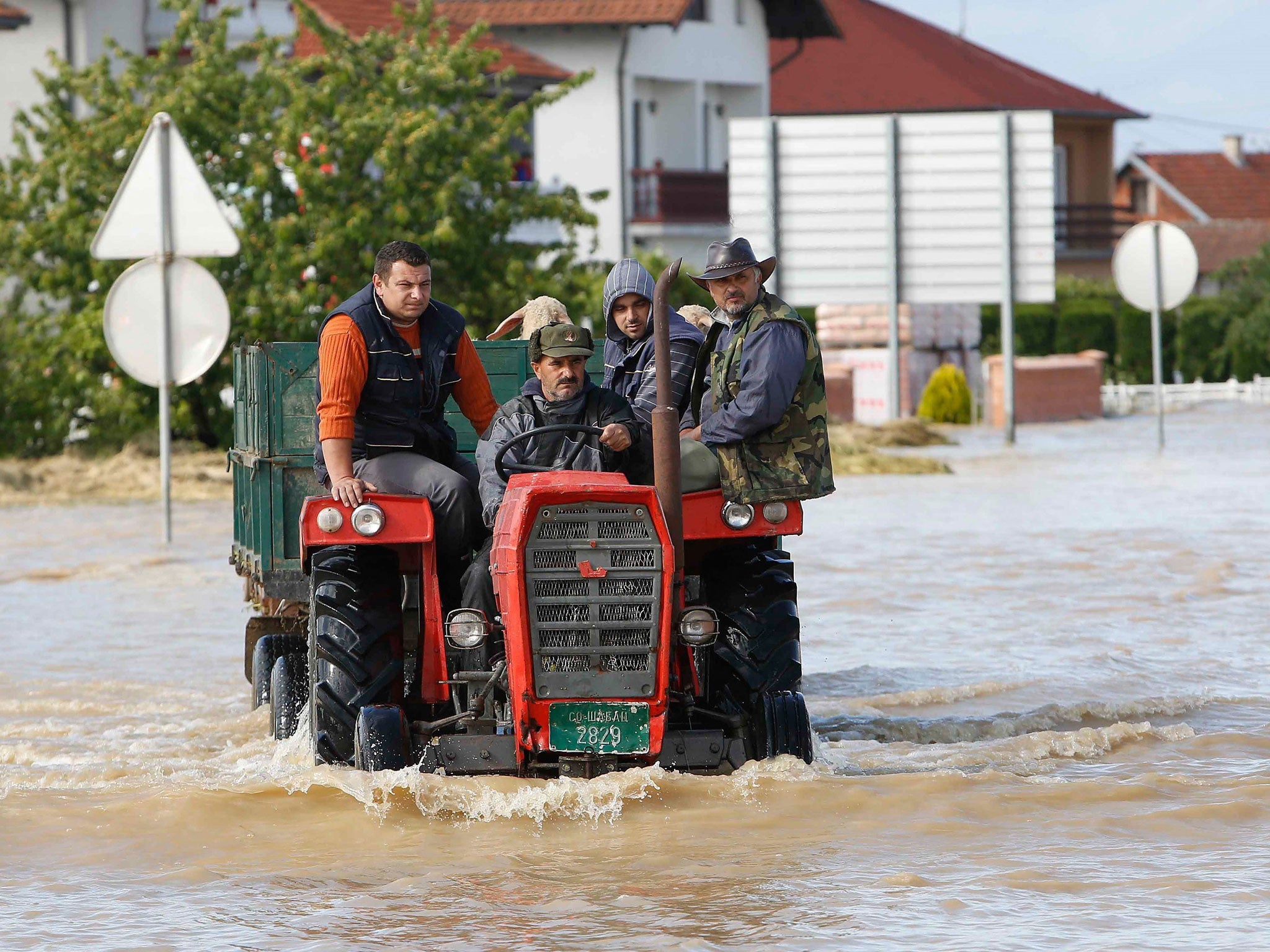 Bosnian men ride a tractor in a flooded street in the Eastern-Bosnian town of Bijeljina