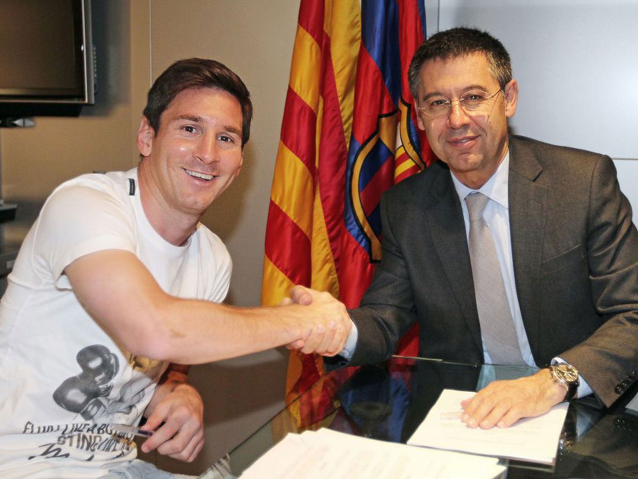 Lionel Messi (left) shakes hands with Barcelona president Josep Maria Bartomeu after signing his new contract yesterday