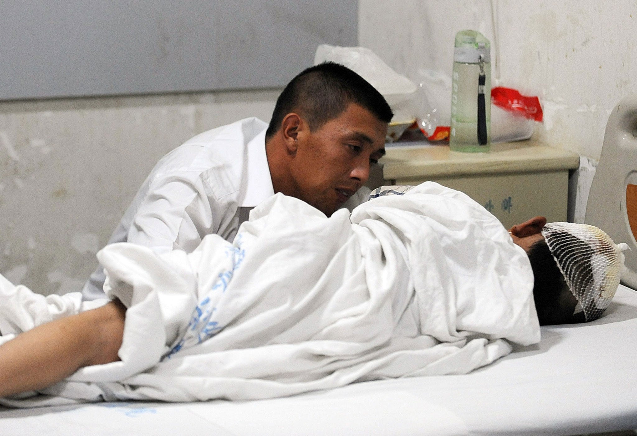 A father by his son's bedside at a hospital in Macheng, Hubei province, following the knife attack