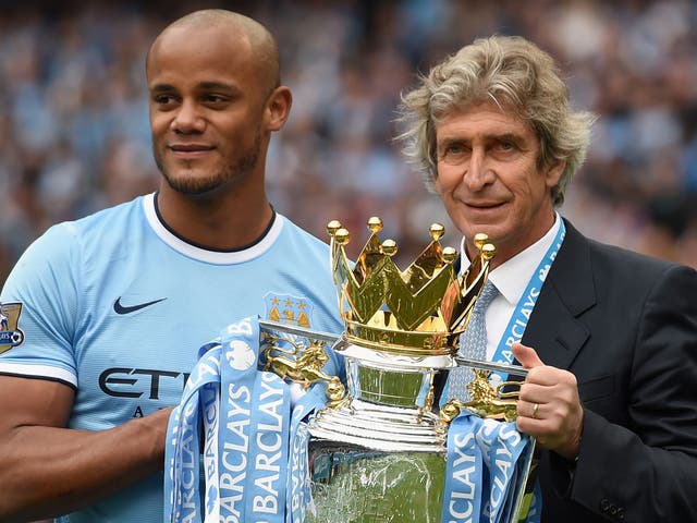 Manchester City manager Manuel Pellegrini holds the Premier League trophy with captain Vincent Kompany