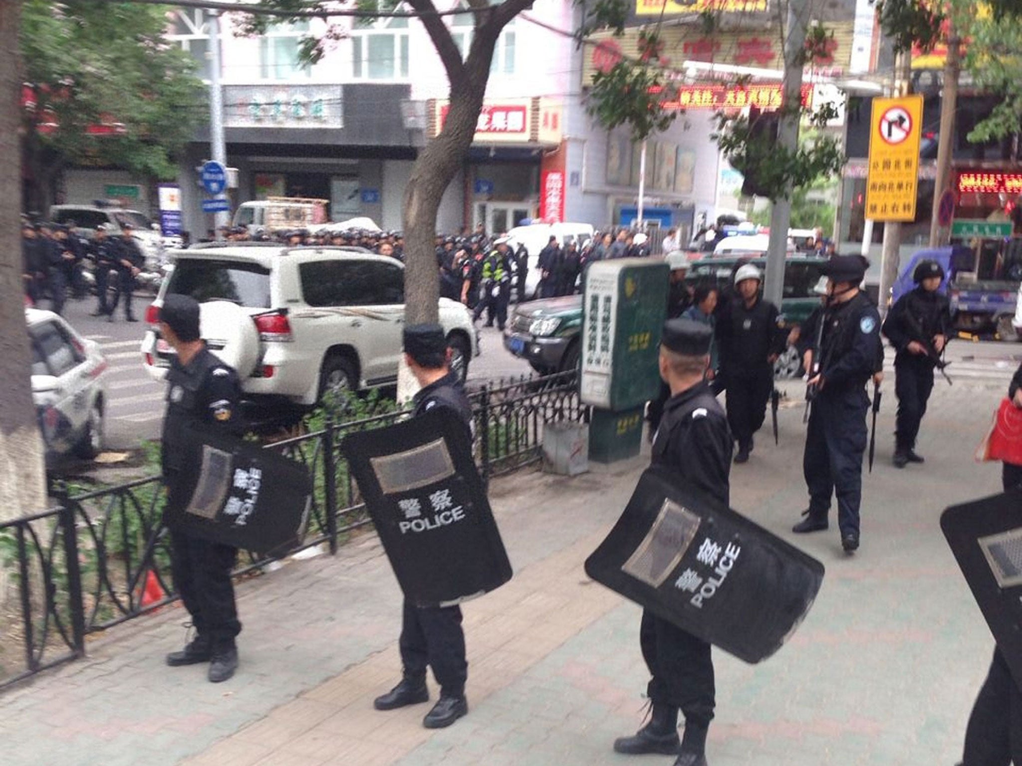 Riot policemen look behind them toward the site of an explosion, which has been cordoned off, as they stand guard in downtown Urumqi