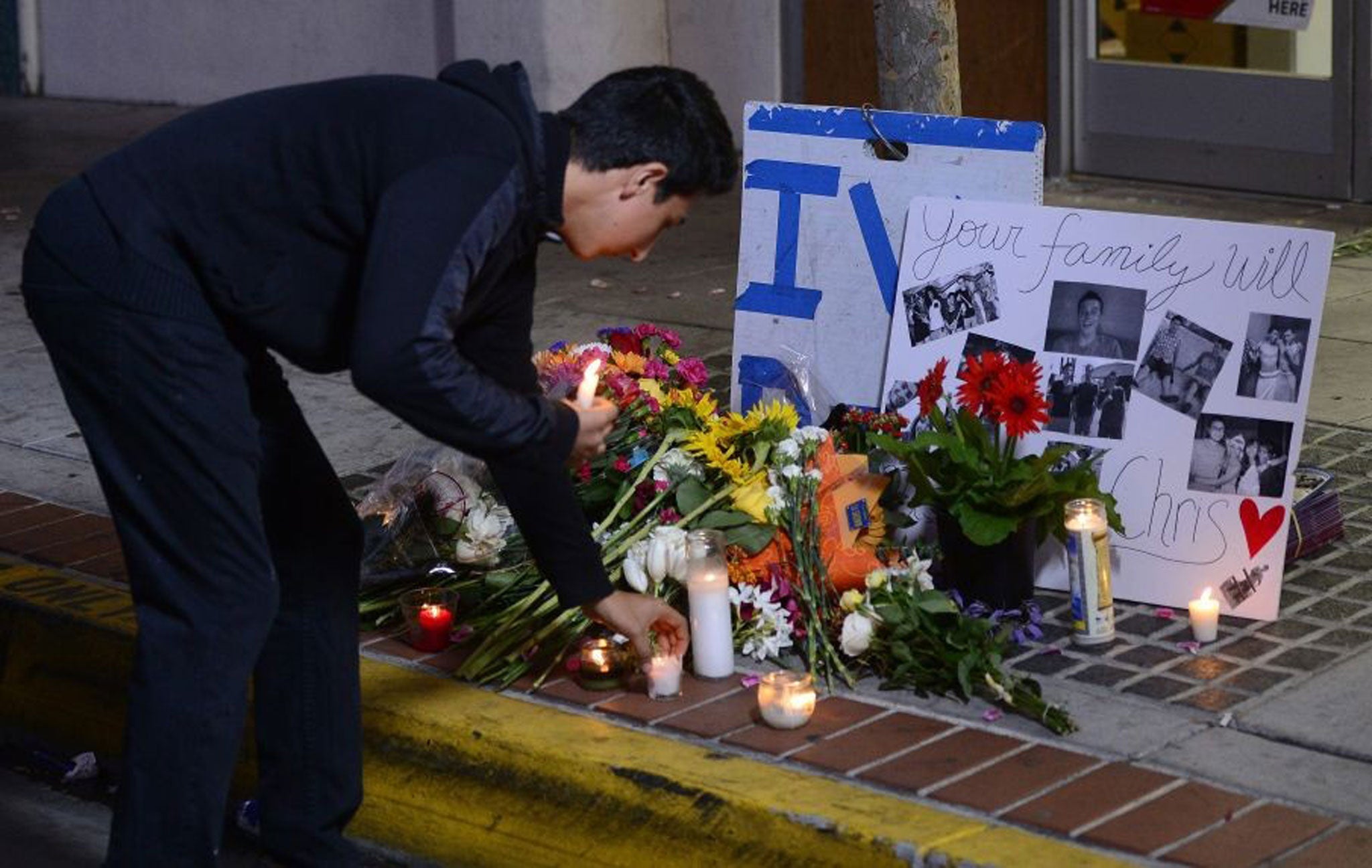 A man places a candle at a makeshift memorial next to the Isla Vista Deli Mart where one of the victims of the deadly shooting rampage was killed at the University of California at Santa Barbara (UCSB) college town of Isla Vista, California