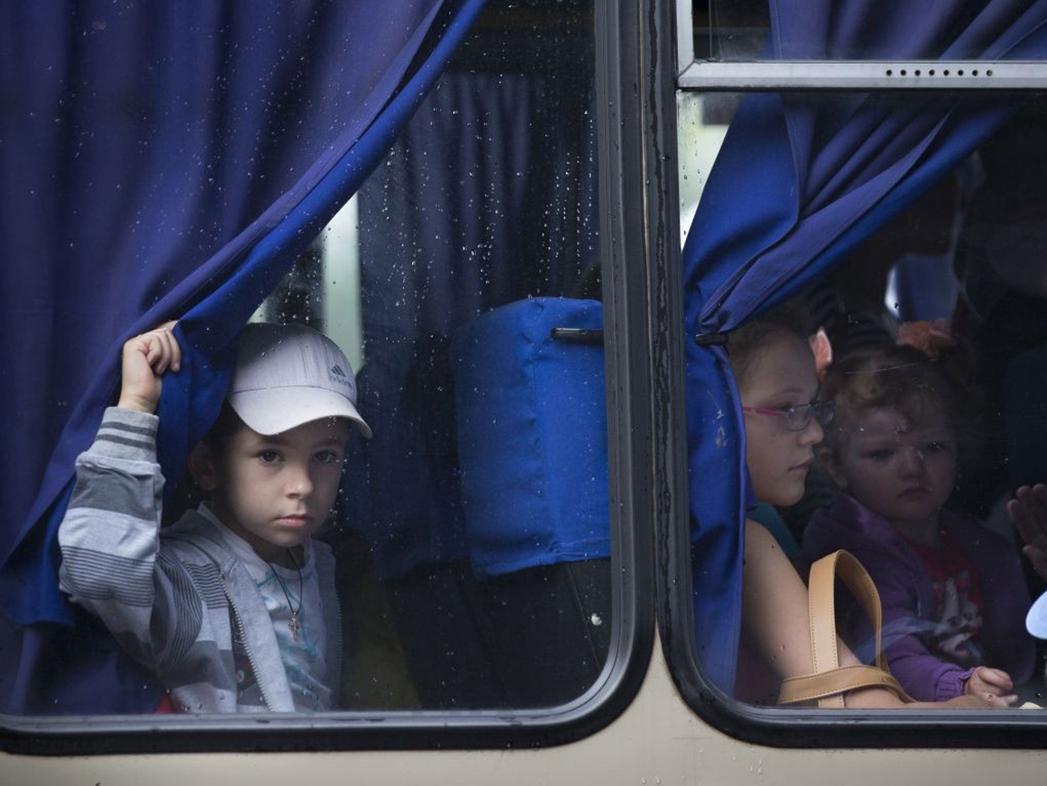 Children look through bus windows while leaving the city fearing shelling attacks during a fighting between Ukrainian government forces and pro-Russian militants in Slovyansk