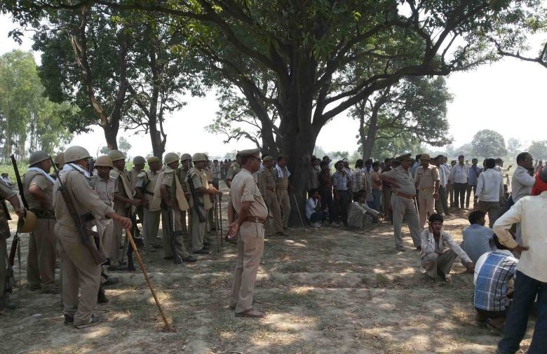 Villagers and policemen gathered where two teenage cousins were found hanging from a mango tree in Katra village